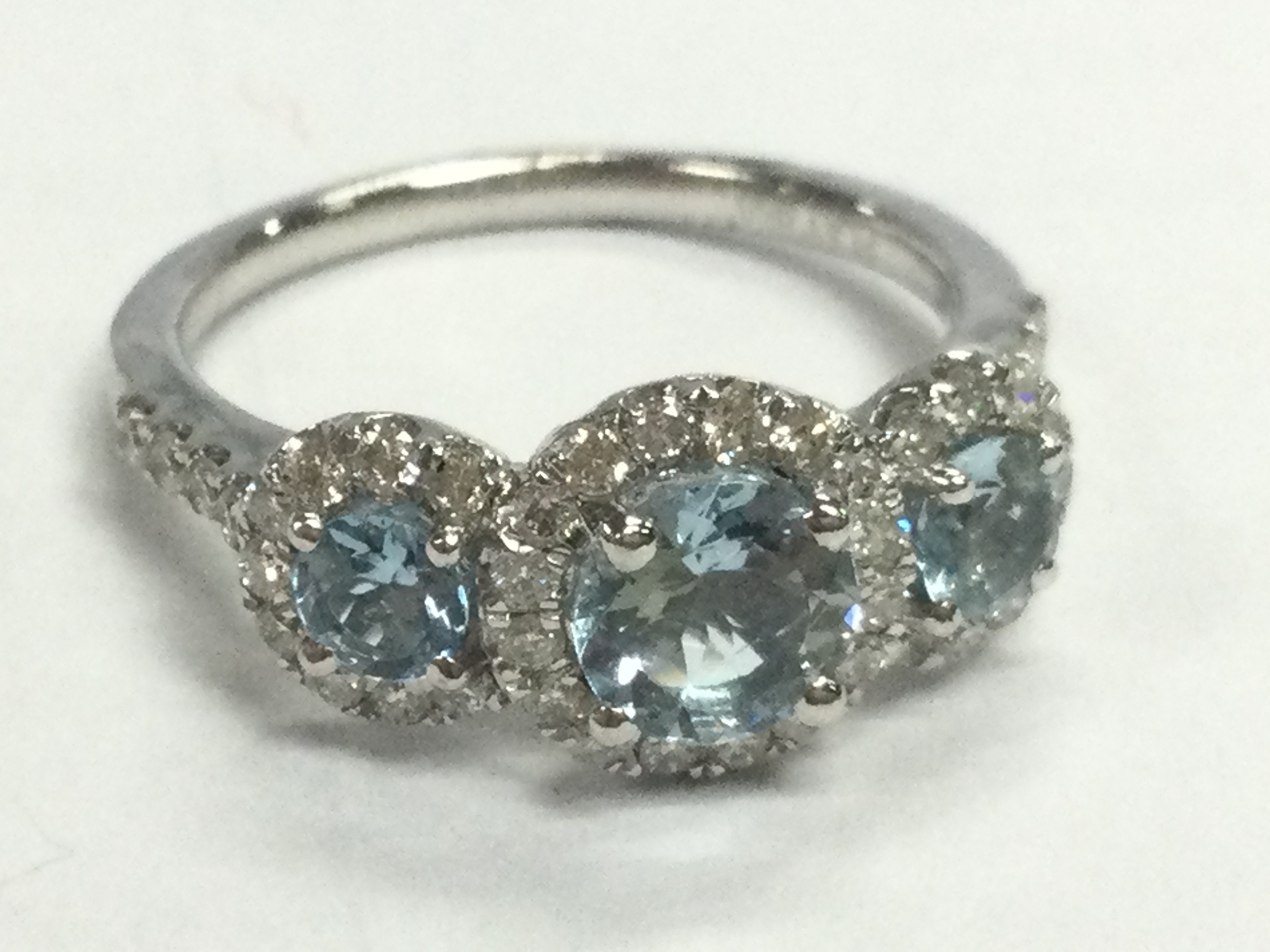 A platinum trilogy cluster ring set with three round aquamarines each surrounded by RBC diamonds, with diamond set shoulders, aquamarines 1.04ct , diamond 0.48ct . Ring Size O.