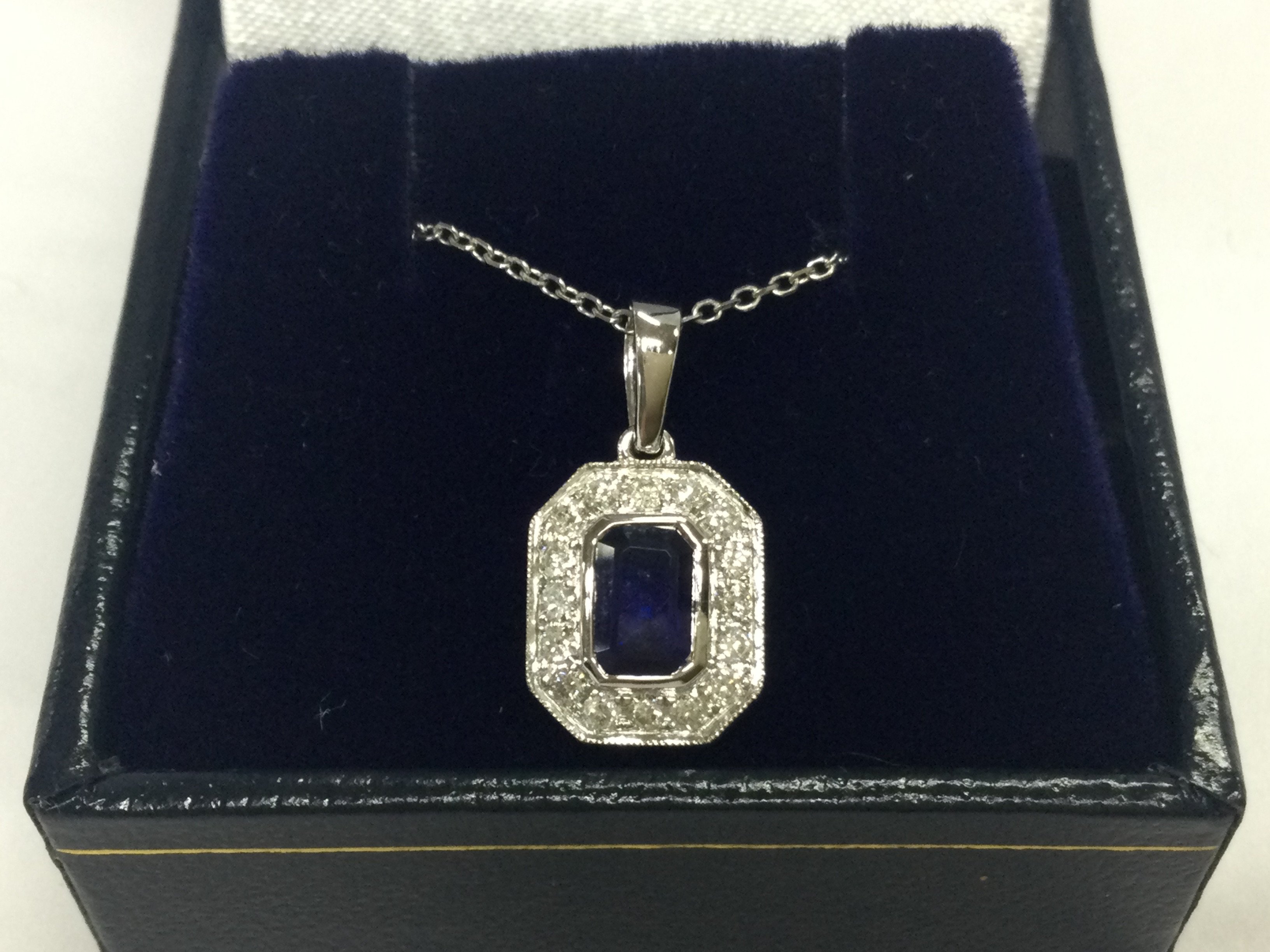 An 18ct white gold step cut sapphire and RBC diamond pendant on a 18ct white gold chain , boxed. Sapphire 0.70ct diamonds 0.24ct. 2.64g total weight. 