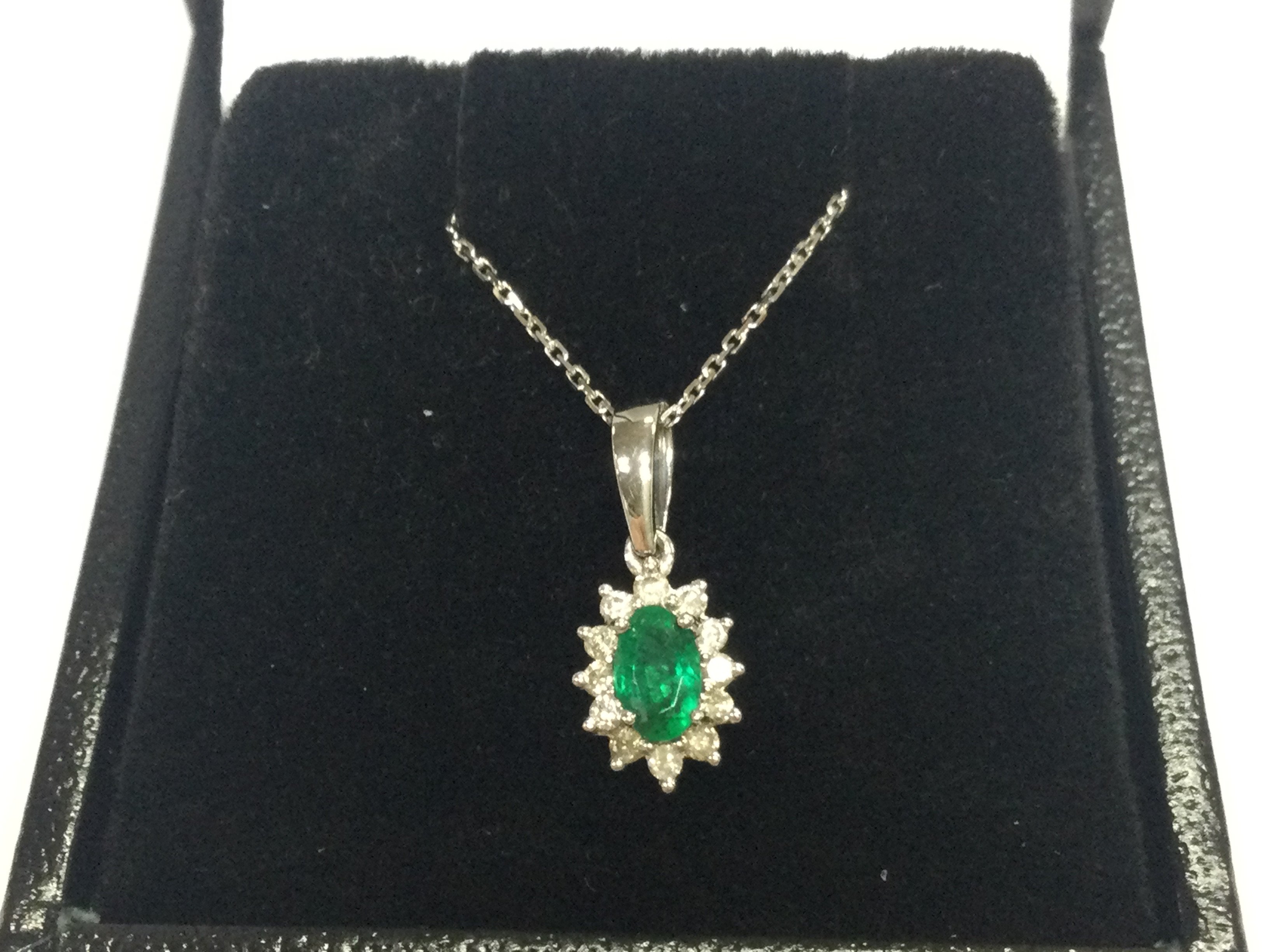 9ct white gold oval emerald and RBC diamond cluster pendant on a 9ct white gold chain, boxed. Emerald 0.22ct , diamonds 0.12ct 