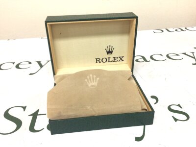 A Rolex watch box finished in green with a wood interior and watch cushion.