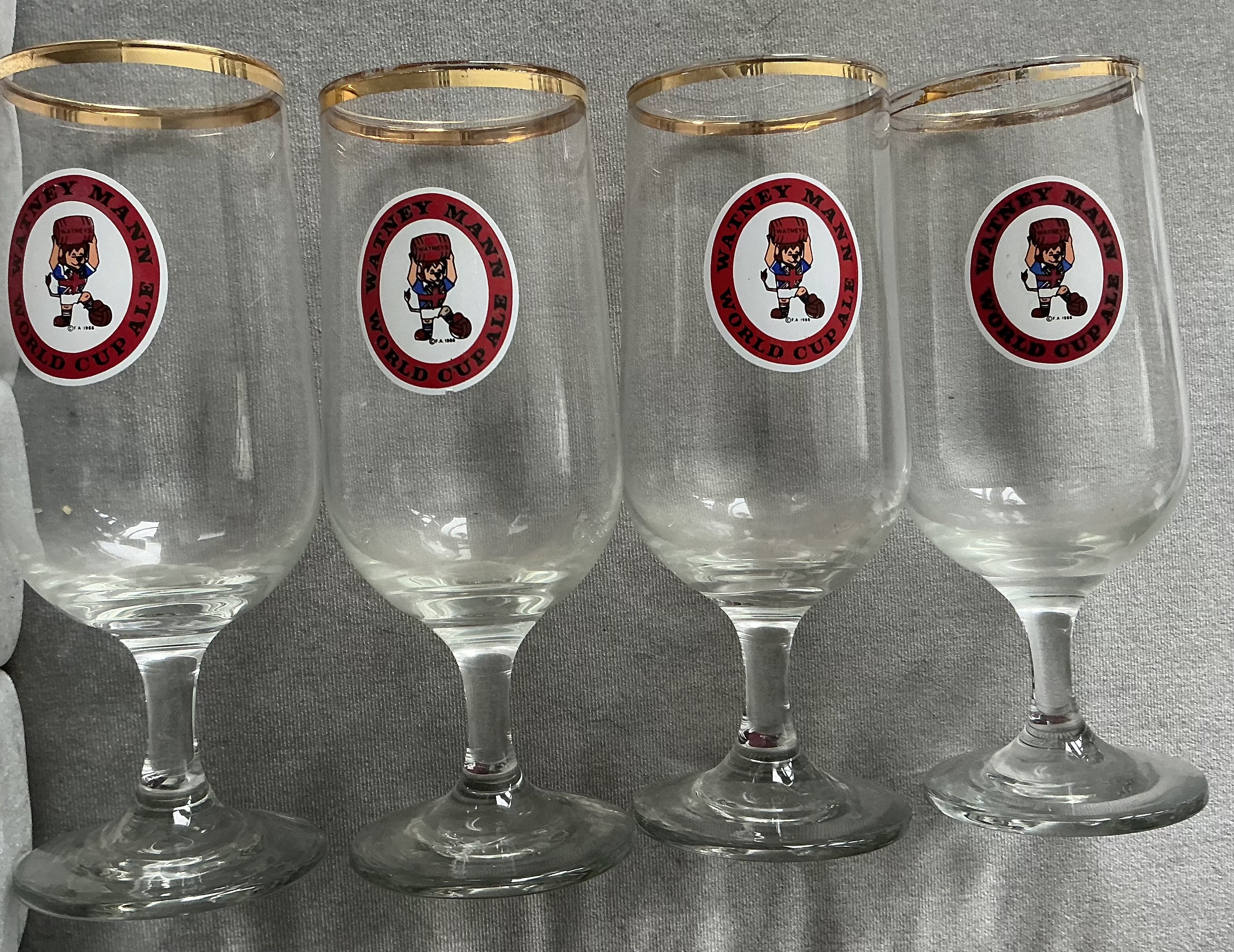 1966 World Cup Watney Mann Drinking Glasses: 4 original half pint glasses with gold rim featuring World Cup Willie holding a barrel inside the words Watney Mann World Cup Ale. (4)
