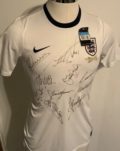 England Signed Legends Football Shirt: 2013 white shirt brand new with tags signed to front by 9 England stars including Hurst Seaman Hoddle Mabbutt and Owen.