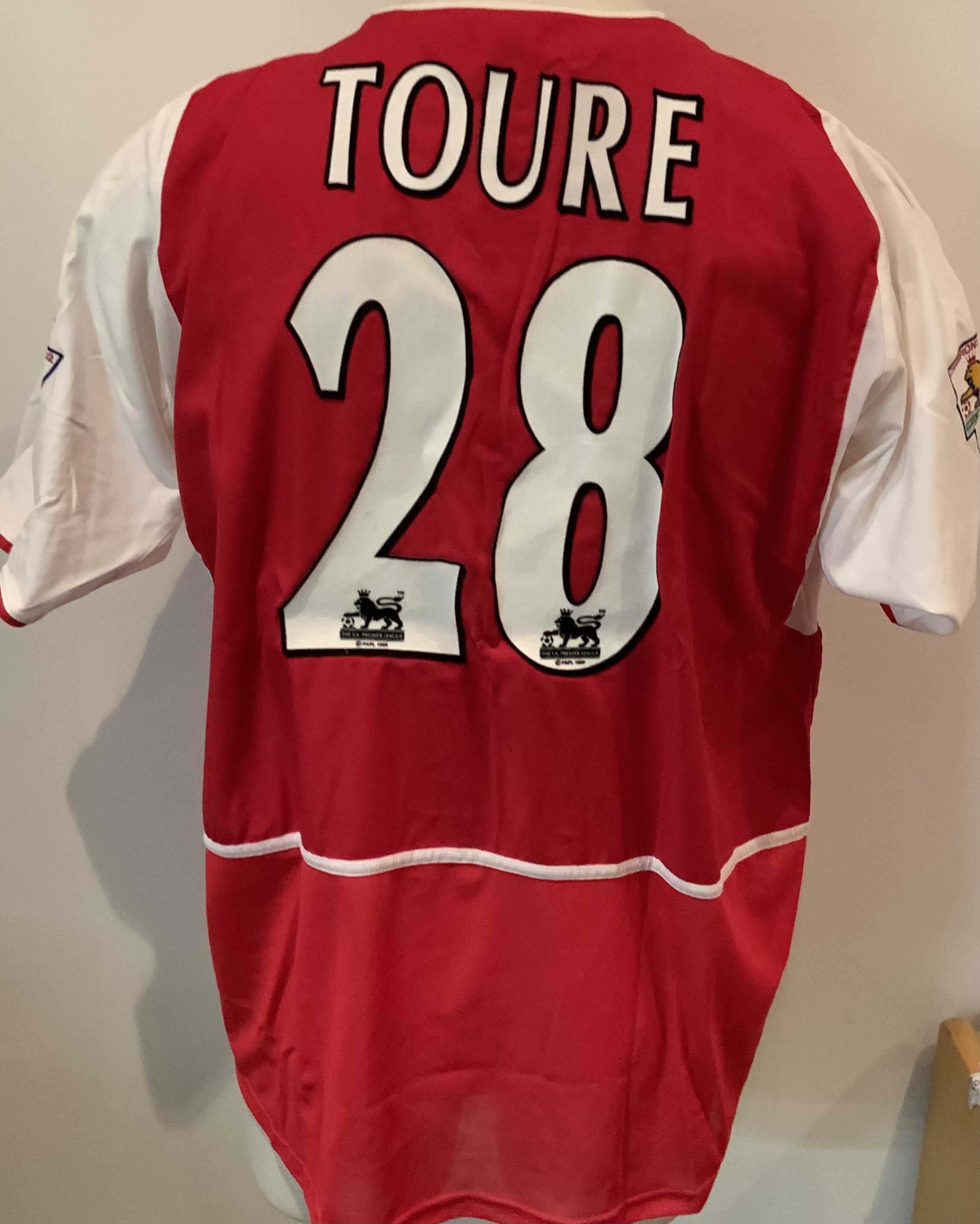 Arsenal Toure 2002 - 2003 Match Worn Home Football Shirt: Nike red short sleeve shirt with O2 sponsorship. Toure 28 to rear and Premier League Winners 2001/2002 sleeve badging. Inner mesh still attached. Some dirt marks to Sponsorship. Worn by Toure on 19 10 2002 with a COA signed by him.