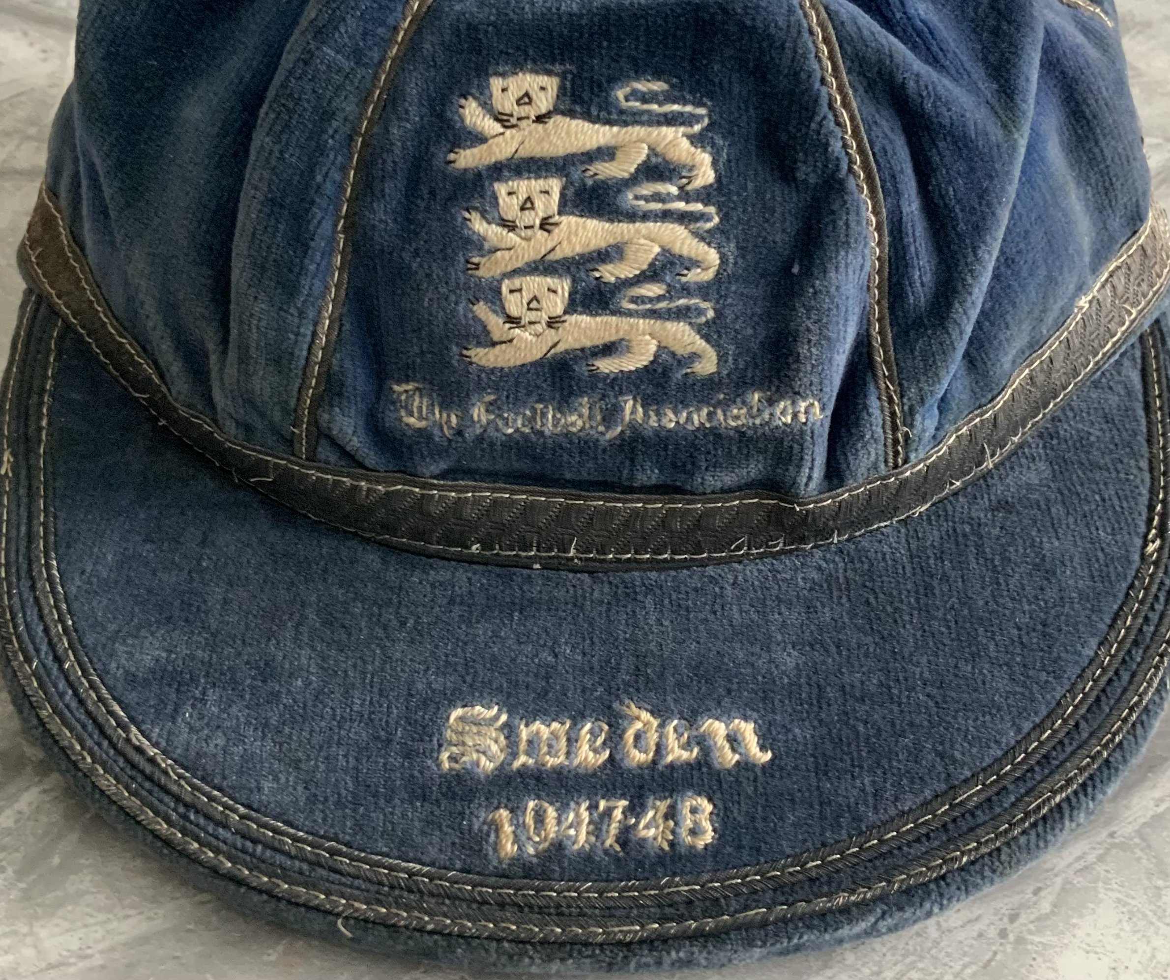 Billy Wright 1947 England International Football Cap: Blue full international cap with three lions to front and the words The Football Association underneath. The peak reads Sweden 1947-48 and refers to the 4- 2 England win in the match played at Arsenal. Billy Wright written inside.