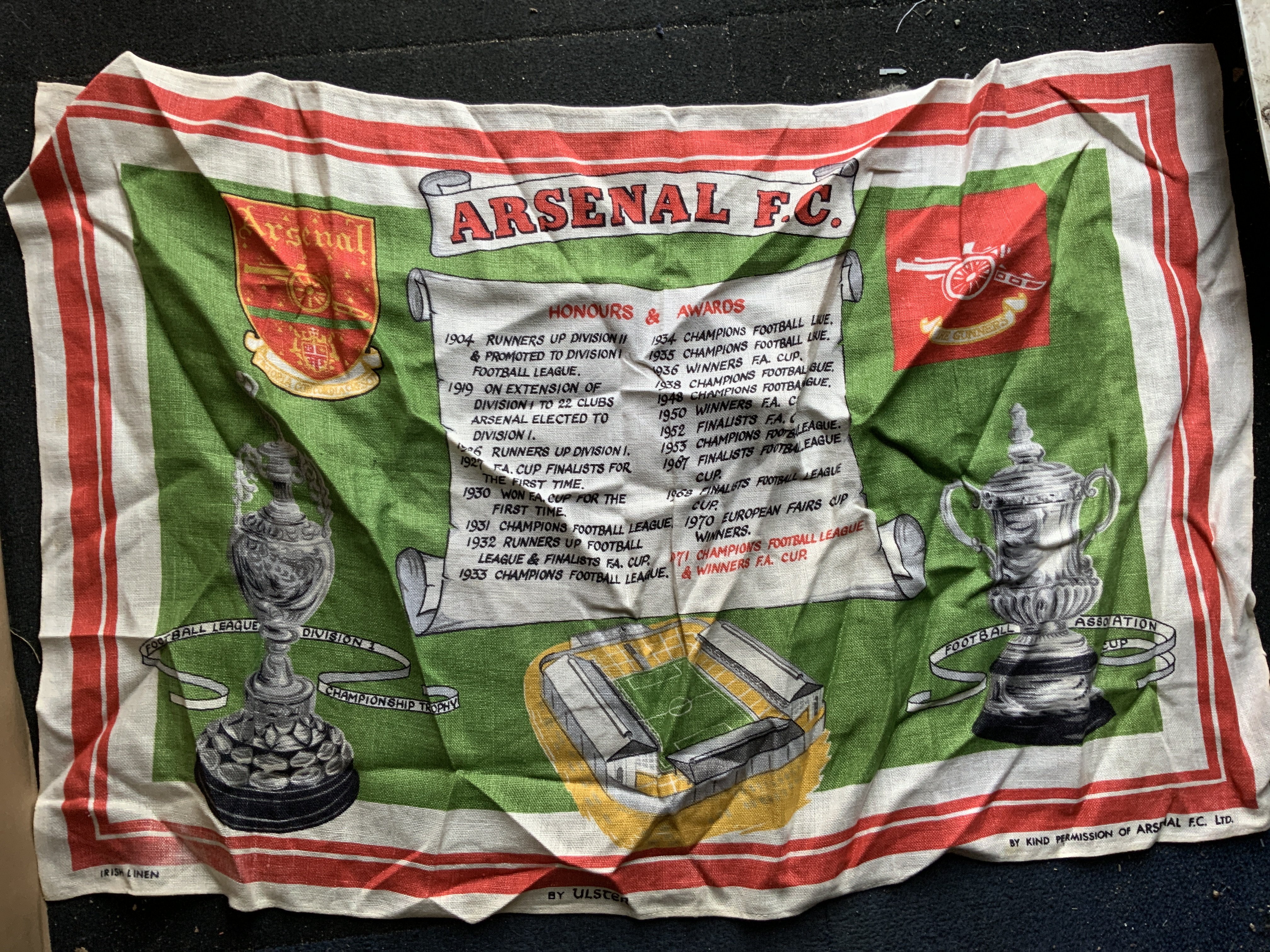 Arsenal Football Memorabilia Box: Includes 64/65 scrapbook, rattle, bed spread. puzzles, quantity of scarves, Irish Linen double team tea towel, mugs, posters, Panini Arsenal large photos in album with autographs to include Rocastle Adams Bould, large 88/89 champions + 1988 Littlewoods Cup flag and much more. Must view.