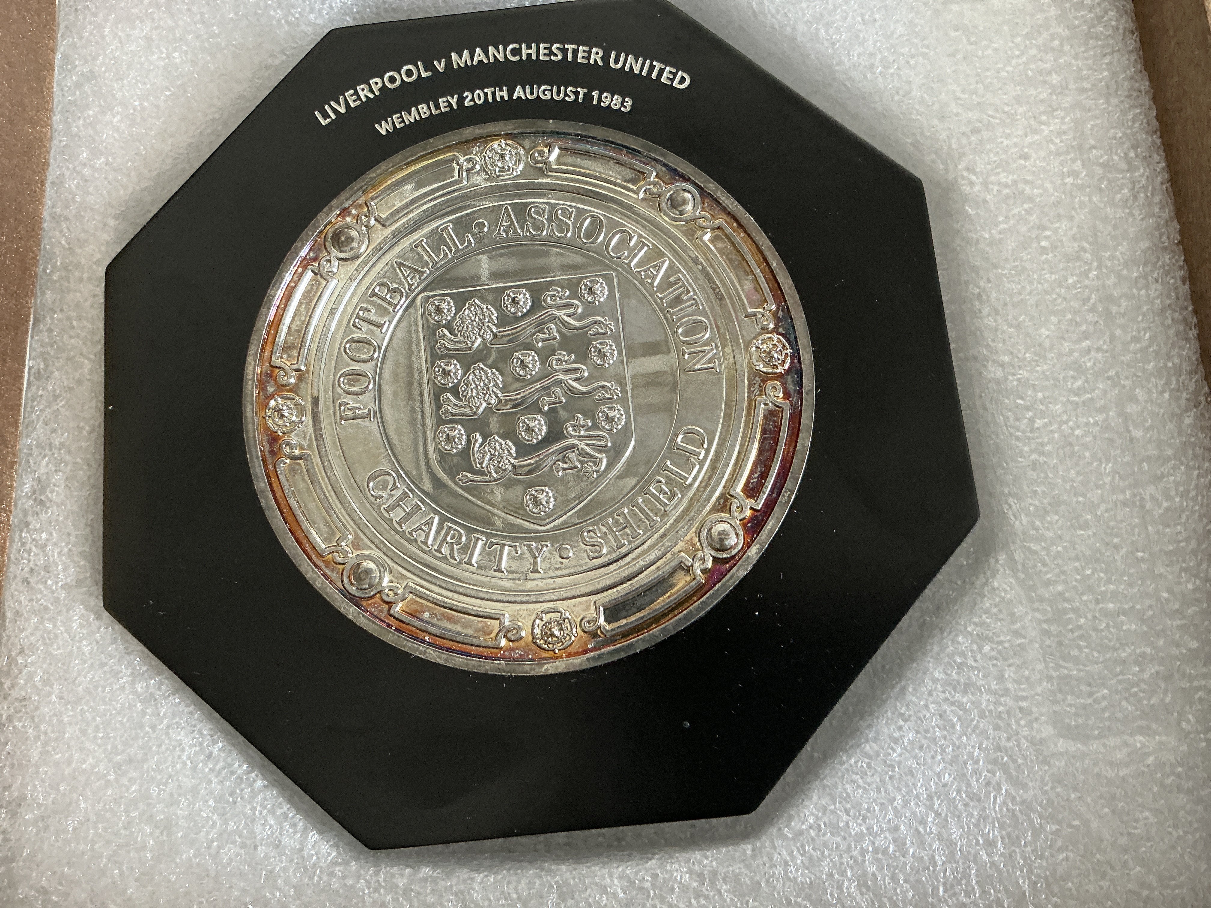 1983 Replica Charity Shield Manchester United v Liverpool Plaque: Identical to ones handed to players that have fixture and date to top. Slight tarnishing to edge of metal. Manchester United won 2-0. Comes in presentation box.
