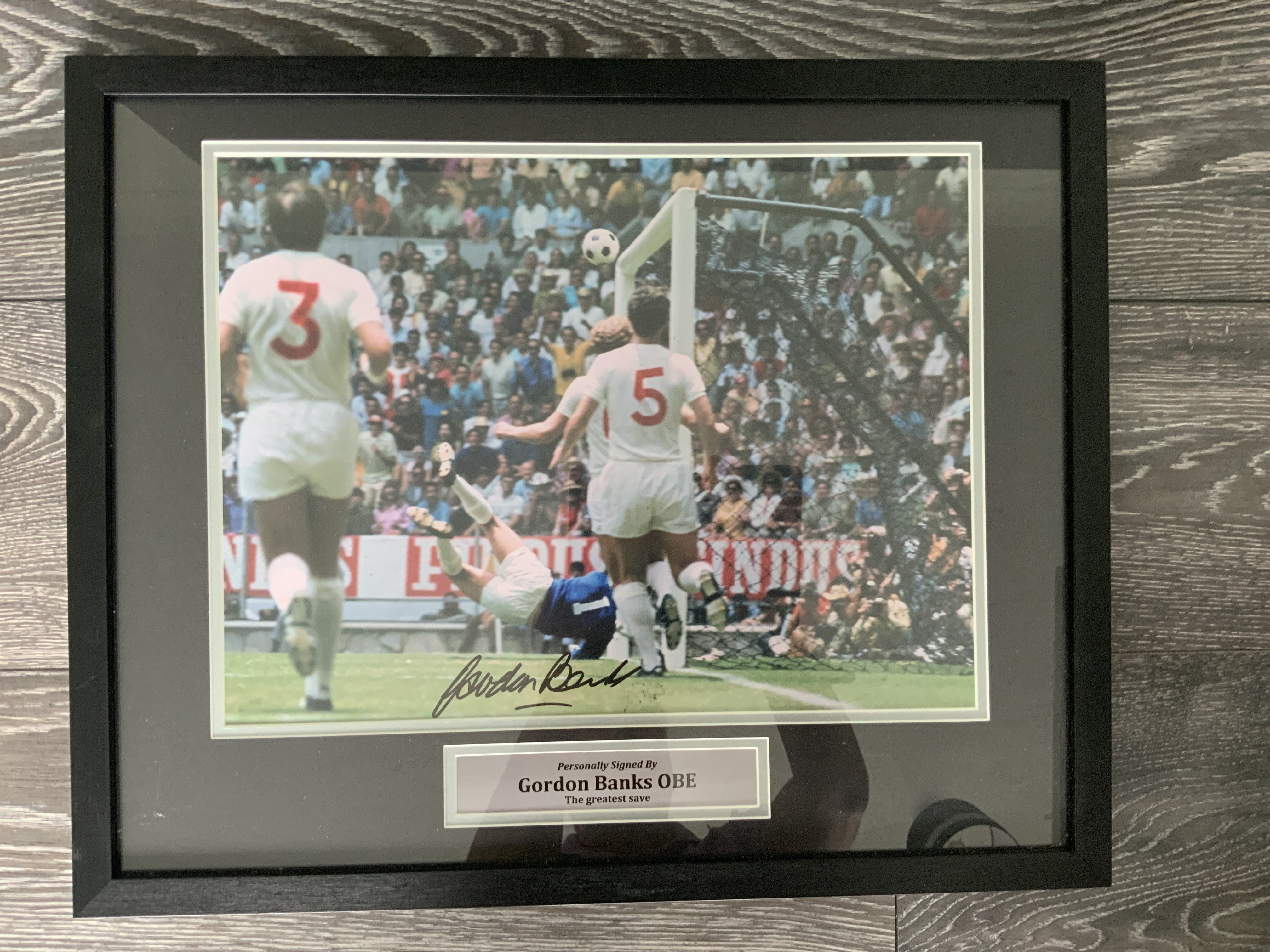 Gordon Banks Greatest Save Signed Framed Photo: Lovely colour photo taken from a side angle of Banks somehow saving from Peles header in the 1970 World Cup. Hand signed with photo proof COA to rear. Measures 21 x 17 inches.
