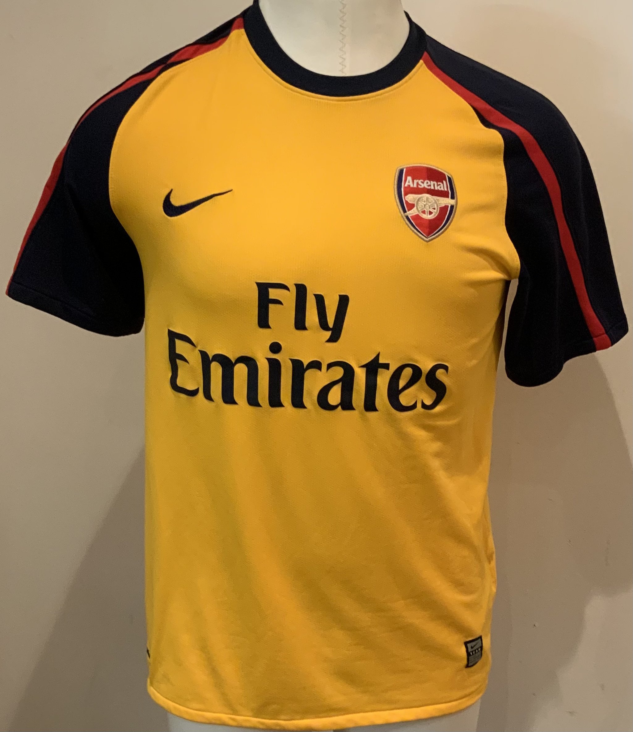 Arsenal Football Shirts: Long sleeve 2010 - 11 home red and white replica Emirates in good condition, size XL with number 9 to rear. Some stains to sleeves. Short sleeve 2008 - 2009 away yellow replica Emirates in good condition. Size medium. (2)