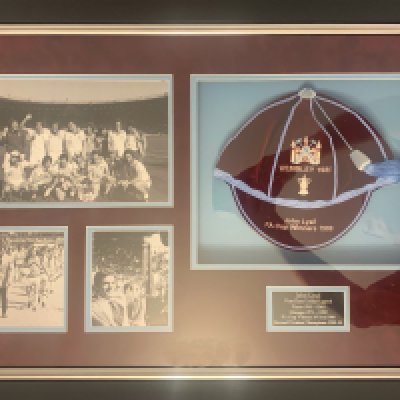 West Ham 1980 FA Cup Winners Football Cap: Stunning framed cap in a quality 800 x 550mm frame which includes photos of the team plus Lyall with trophy and leading the team out. COA from Gentlemen and Players caps who along with Tony Gale presented the cap on 11 10 2018 to the family of John Lyall.