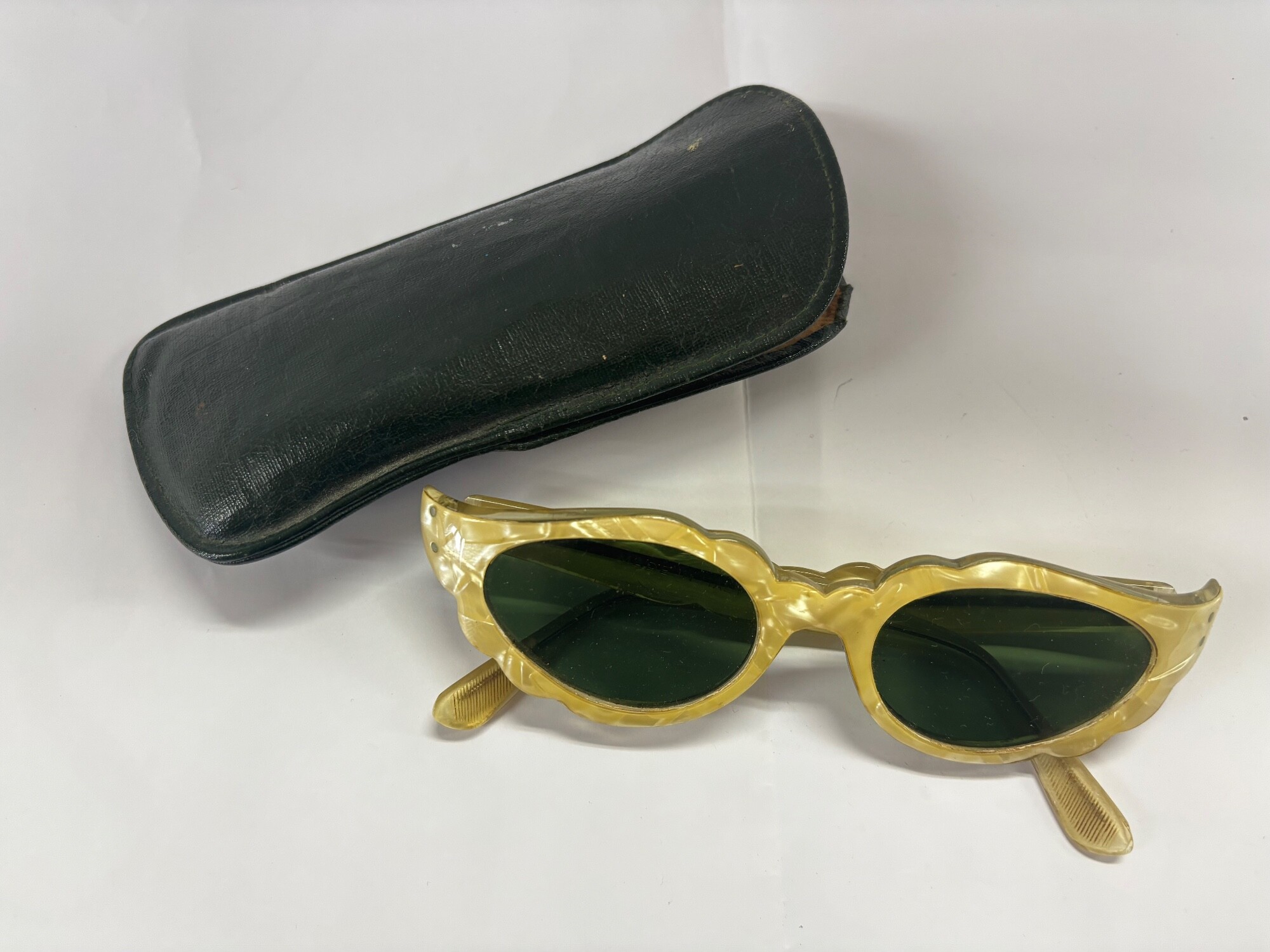 A pair of late 1950 or early 1960s Italian simulated mother of pearl sunglasses with a green case.