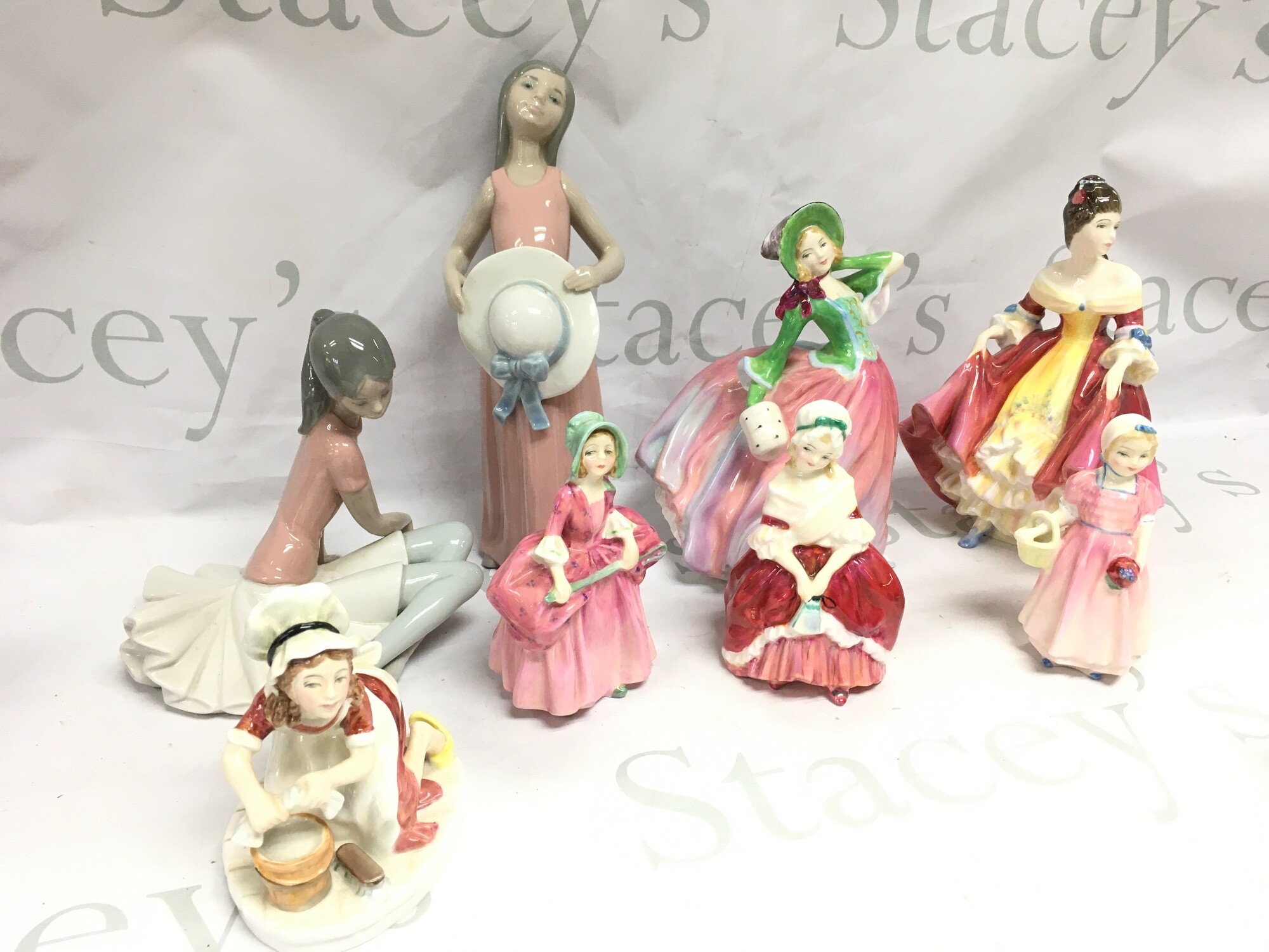 A collection of Lladro and Royal Doulton figures including Autumn Breezes, Southern Belle and coloured Victorian and later drinking classes