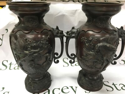 A pair of bronze Japanese vases with decorations of cranes and birds of prey finely sculpted among flowering branches. Marks to base (One handle missing), 37cm tall.