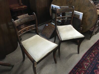 A pair of Regency mahogany and gilt inlaid design dining chairs with carved top rails and sabre legs. 83cm tall 48cm wide