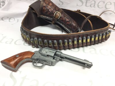 A Cowboy Western style leather gun holster and belt with a replica revolver.