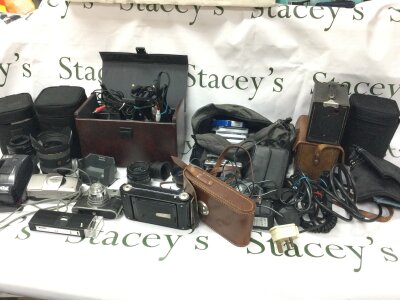 A collection of mixed cameras and camera equipment including lenses, cables etc.