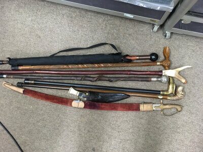 A collection of walking sticks, an Indian sword and a Kukri knife.
