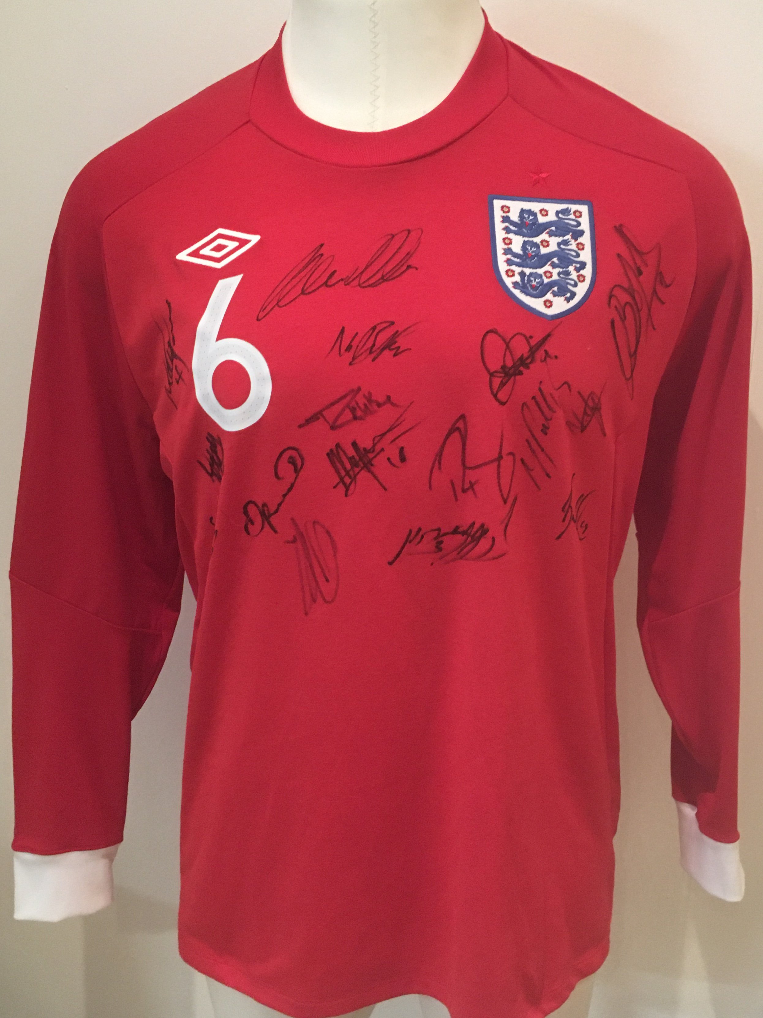 2010 England U21 Signed Football Shirt: Official England red long sleeve number 6 shirt signed by 16 players brought back by Peter Barnes the Tottenham + West Ham club secretary who travelled with the touring party. Please note this is not a match worn shirt.
