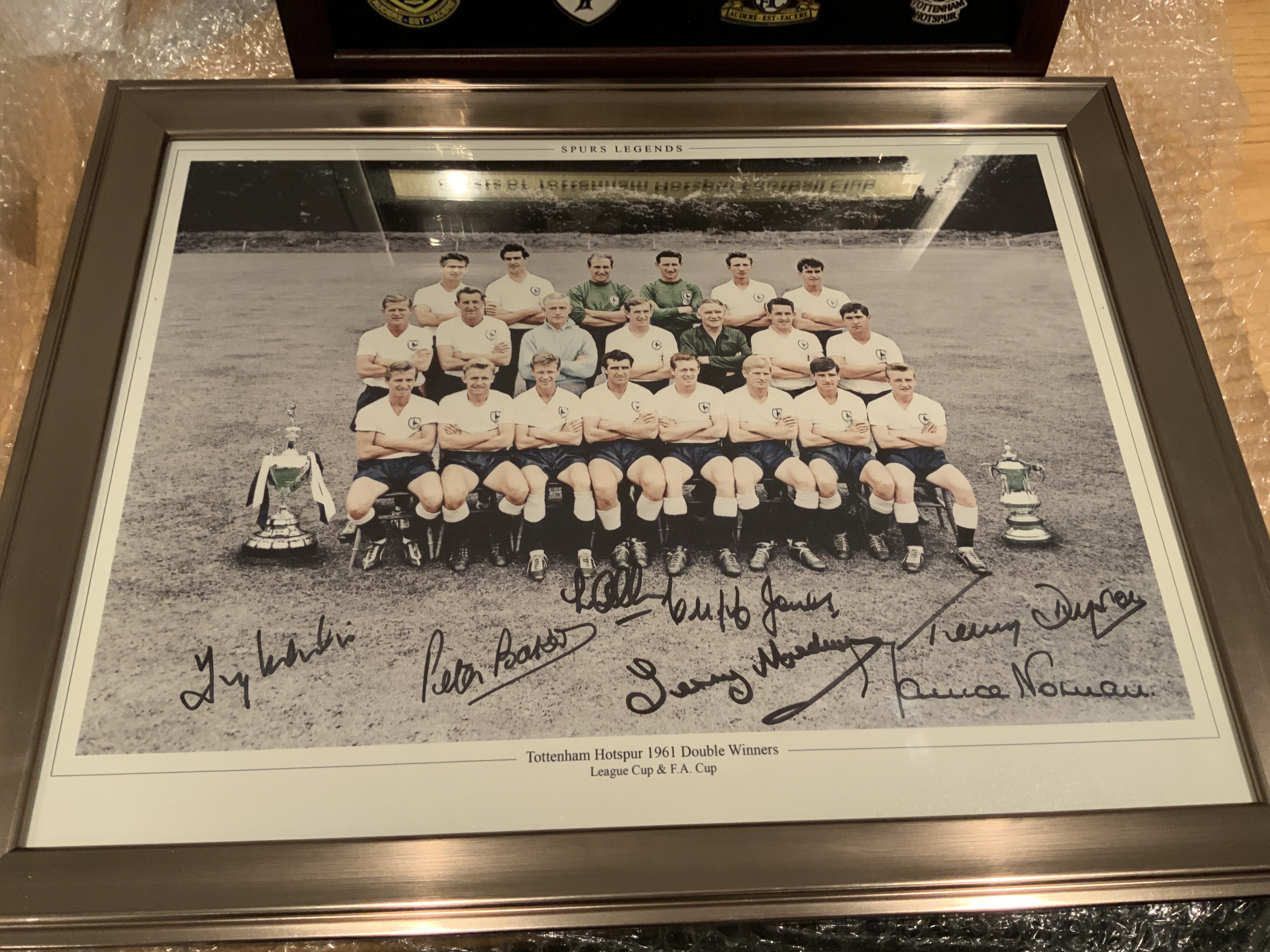 Tottenham 1961 Double Team Signed Framed Photo: 18 x 14 inch framed photo of the 1961 team hand signed by Marchi Baker Allen Jedwin Norman Dyson and Jones. C/W framed 8 historic crests of Spurs. (2)