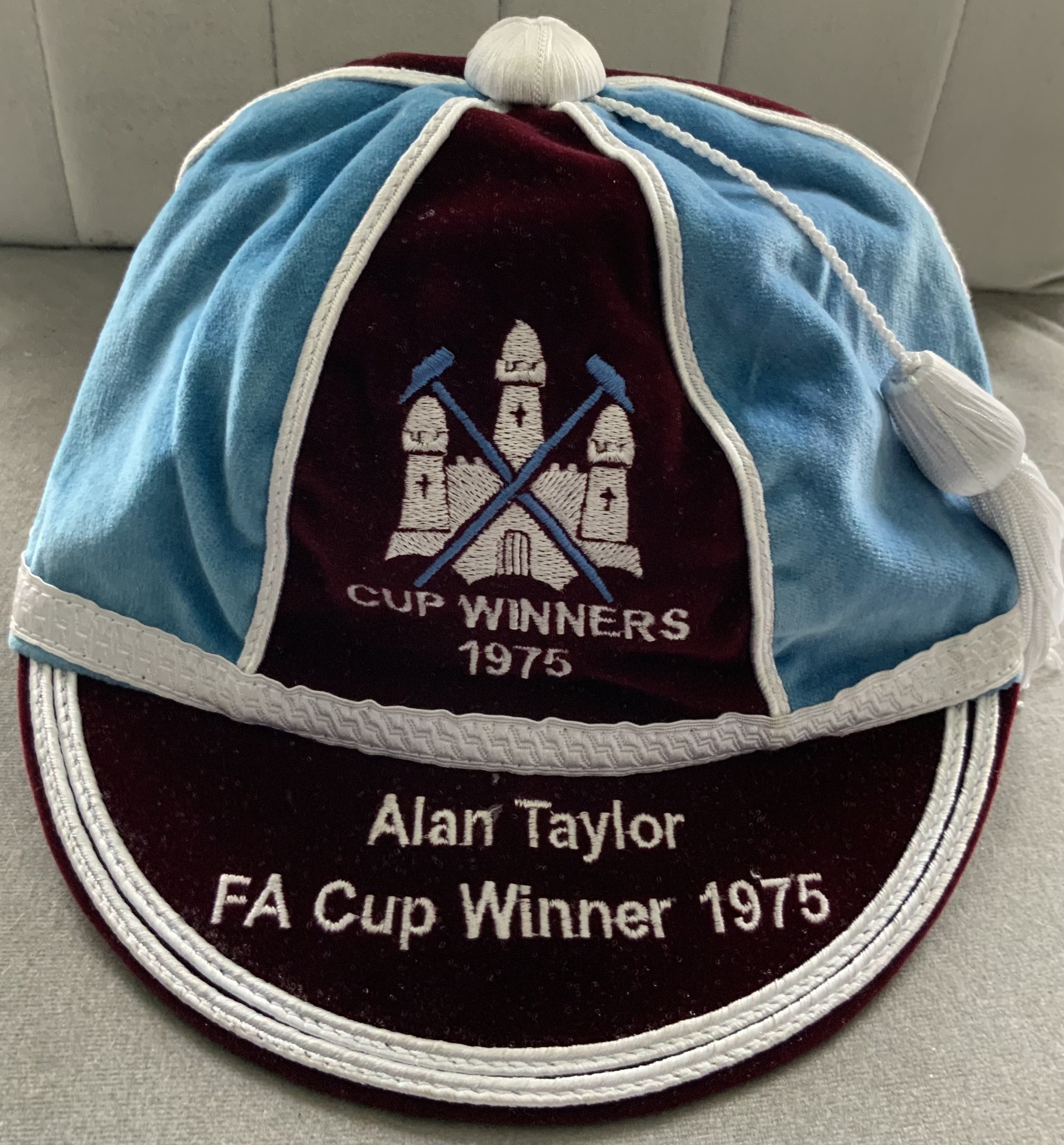 Alan Taylor West Ham FA Cup Final Football Cap: Claret and blue attractive cap with embroidery of the club badge above Cup Winners 1975 wording. Peak has Alan Taylor FA Cup Winner 1975. Certificate from Gentlemen and Players fine traditional caps. Comes in quality box. C/W a few gifts given to Taylor which include 1975 related badges and coasters.