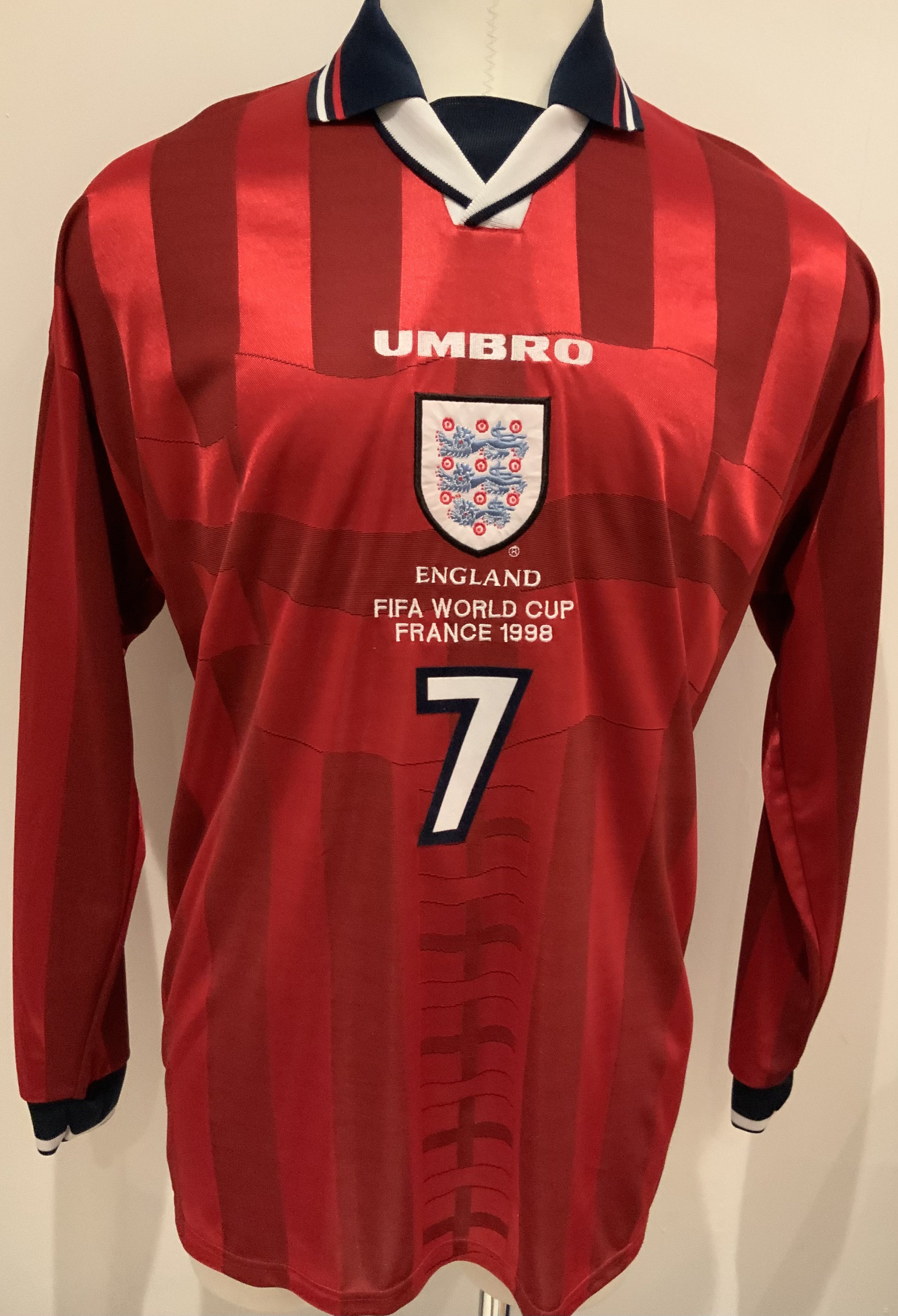 David Beckham 1998 World Cup Tournament Issued Football Shirt: Red long sleeve Umbro shirt with number 7 Beckham to rear. Front has England badge under Umbro then the words England FIFA World Cup France 1998 above number 7. Given by Davids father to vendor and not to be mixed up with similar replicas which have slight differences including the R copyright placement. Excellent.