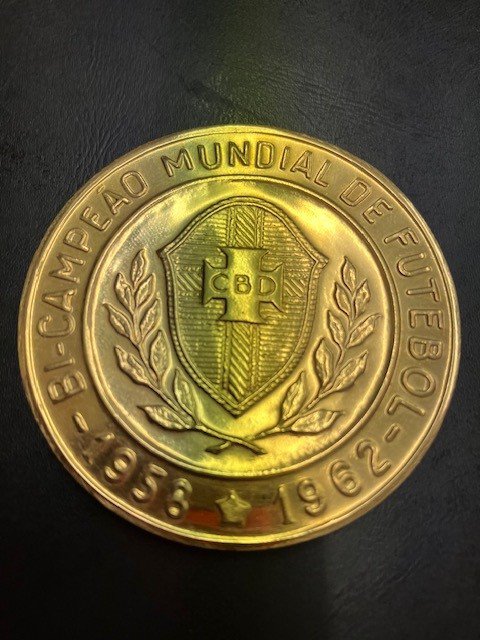 1970 World Cup FIFA Gold Football Medal: To celebrate winning the World Cup for the 3rd time the Brazil team including Pele Felix Rivellino Tostao etc attended an event held by FIFA. The same medal was presented to English referee Ken Aston who was in charge of referees for the whole tournament and fundamental in bringing in new ideas including red and yellow cards to the World Cup tournament. The medal we have been advised is 21carat Brazilian gold weighing 101 grammes and its 5cm diameter is hallmarked. Rare medal indeed.