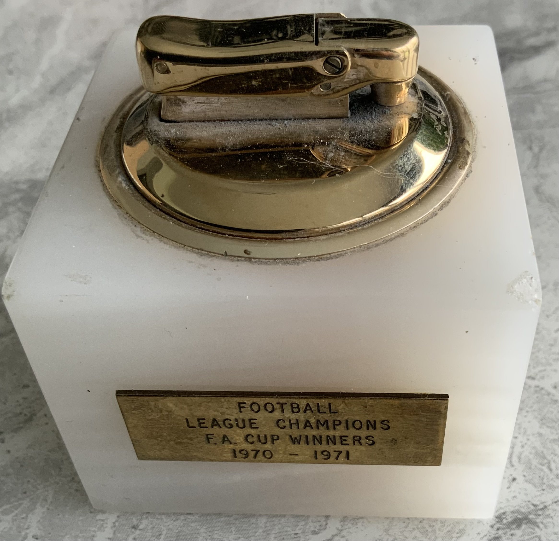 Arsenal Double Team 70/71 Football Lighter: Heavy marble lighter with one side stating Football League Champions FA Cup Winners 1970 - 1971. Reverse has an enamel badge of Arsenal. Lighter produced by Calibri is not in working order. Presented by the club.
