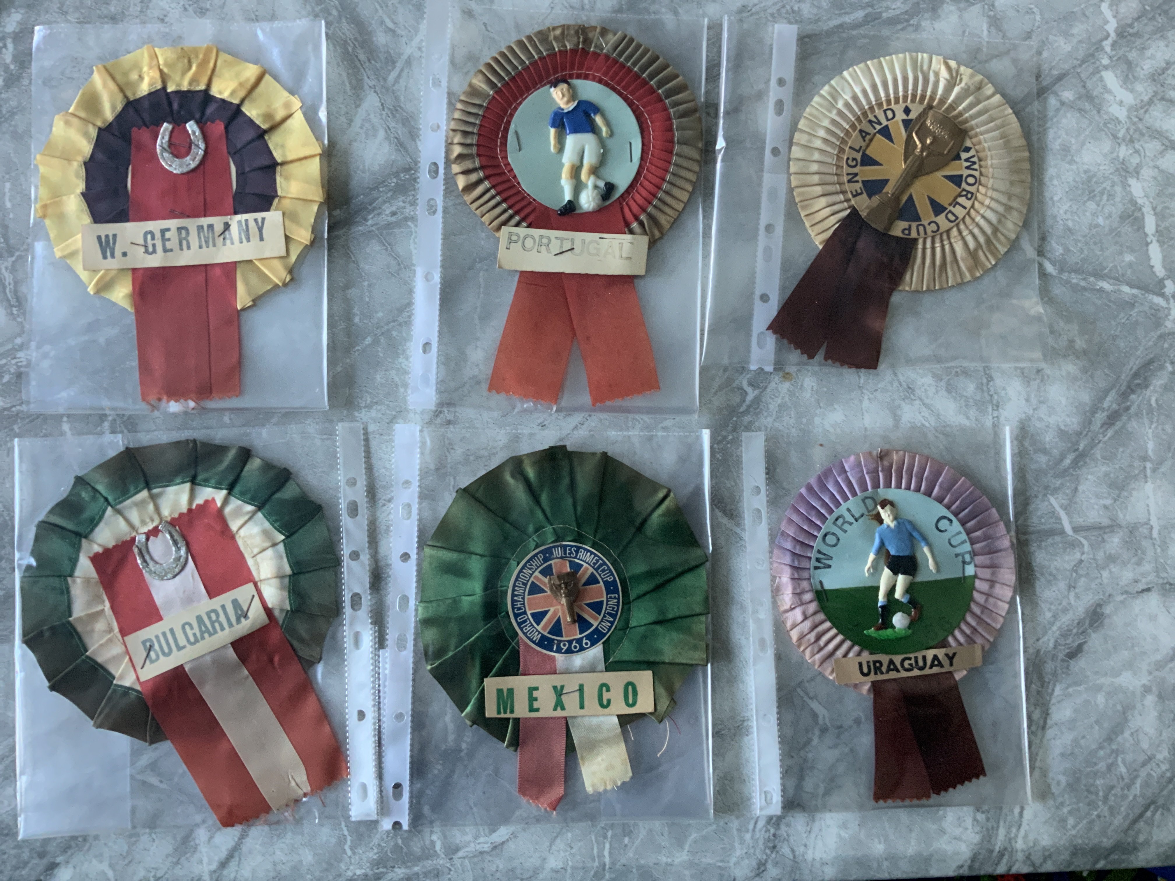 1966 World Cup Football Rosettes: England Uruguay and Mexico actually state a World Cup with two having the Jules Rimet trophy. Bulgaria West Germany and Portugal are of the period but do not state World Cup. Good. (6)
