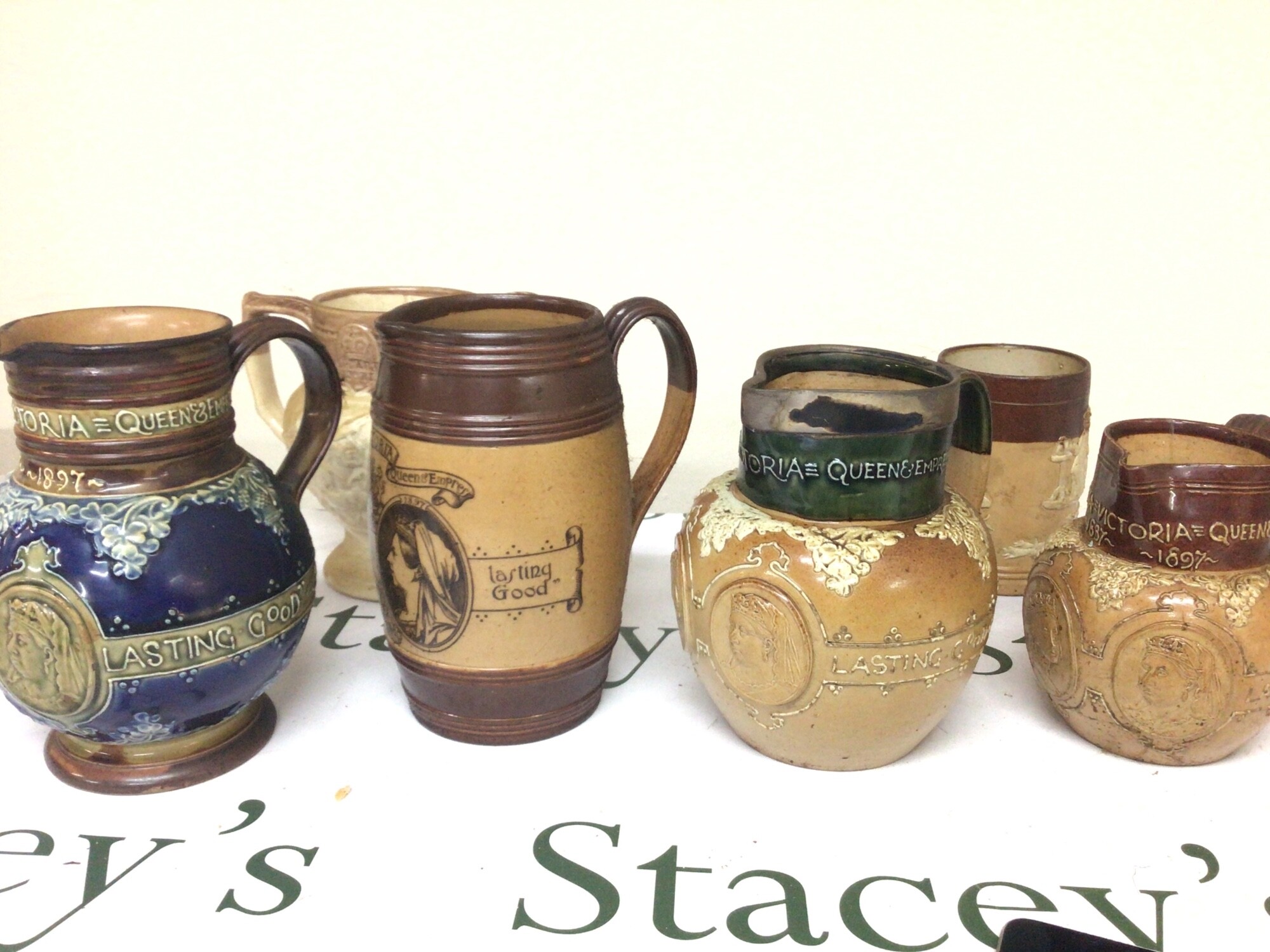 A collection of Doulton stoneware Victorian jugs Jubilee commemorative one with a silver collar. One stamped Thomas Wallis Holborn Circus. (6)