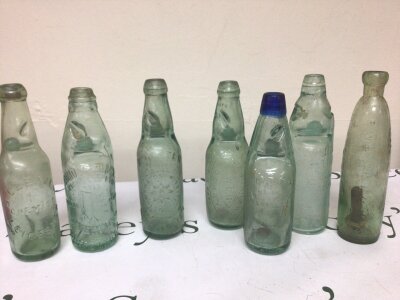 A Collection of seven Antique Codd bottles each with moulded trade labels including an unusual example with a blue glass top (7) NO RESERVE.