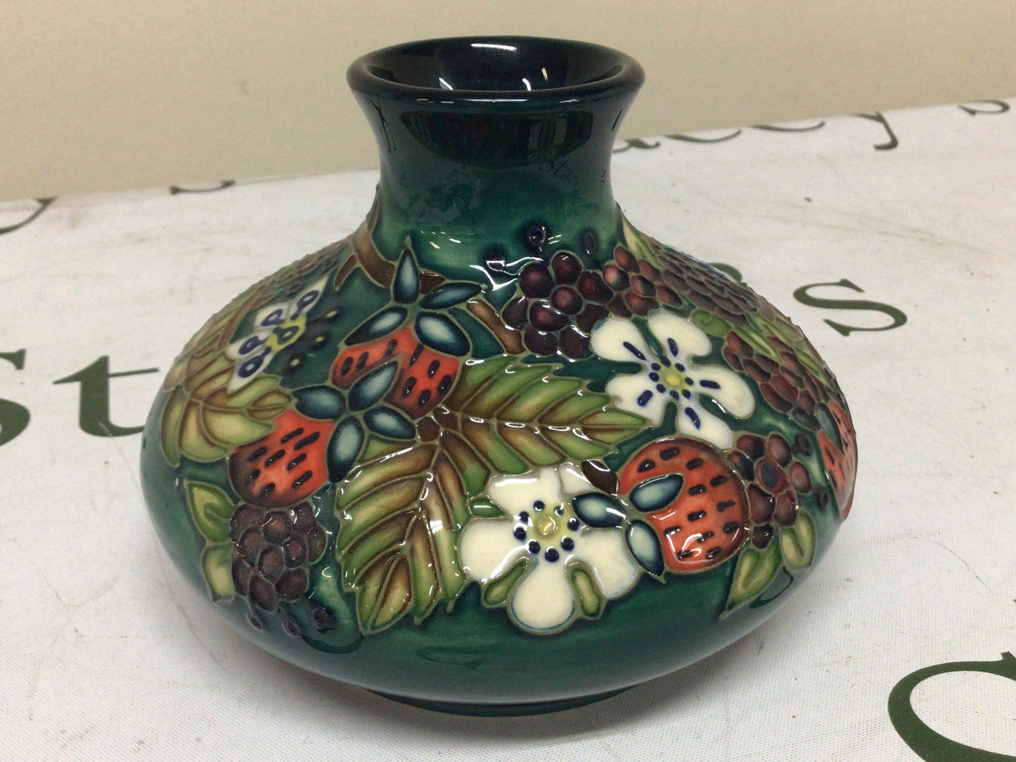 A Moorcroft vase decorated with raised fruit and flowers.