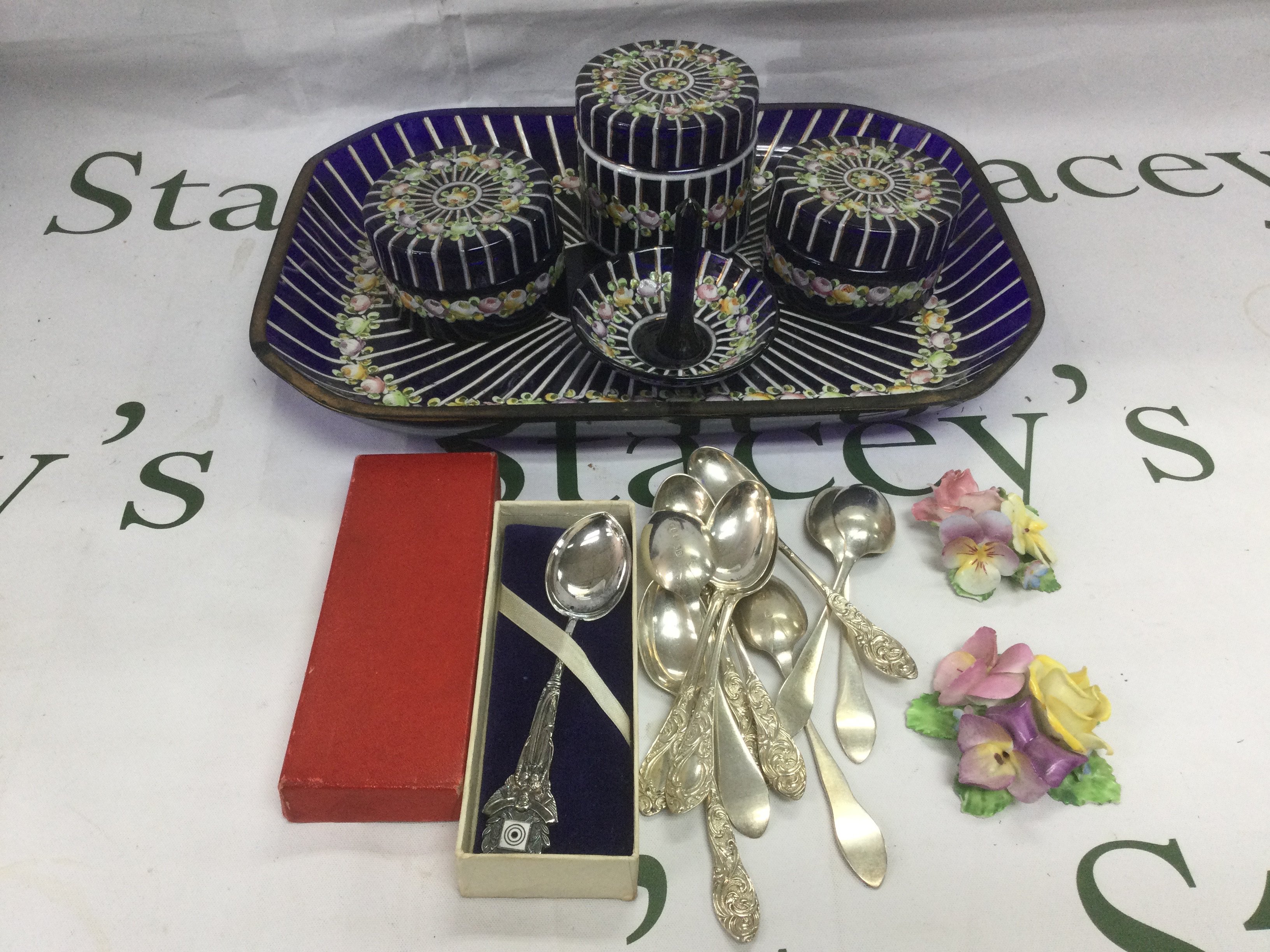 A glass dressing table set decorated with flowers plus some spoons etc. Shipping category D.