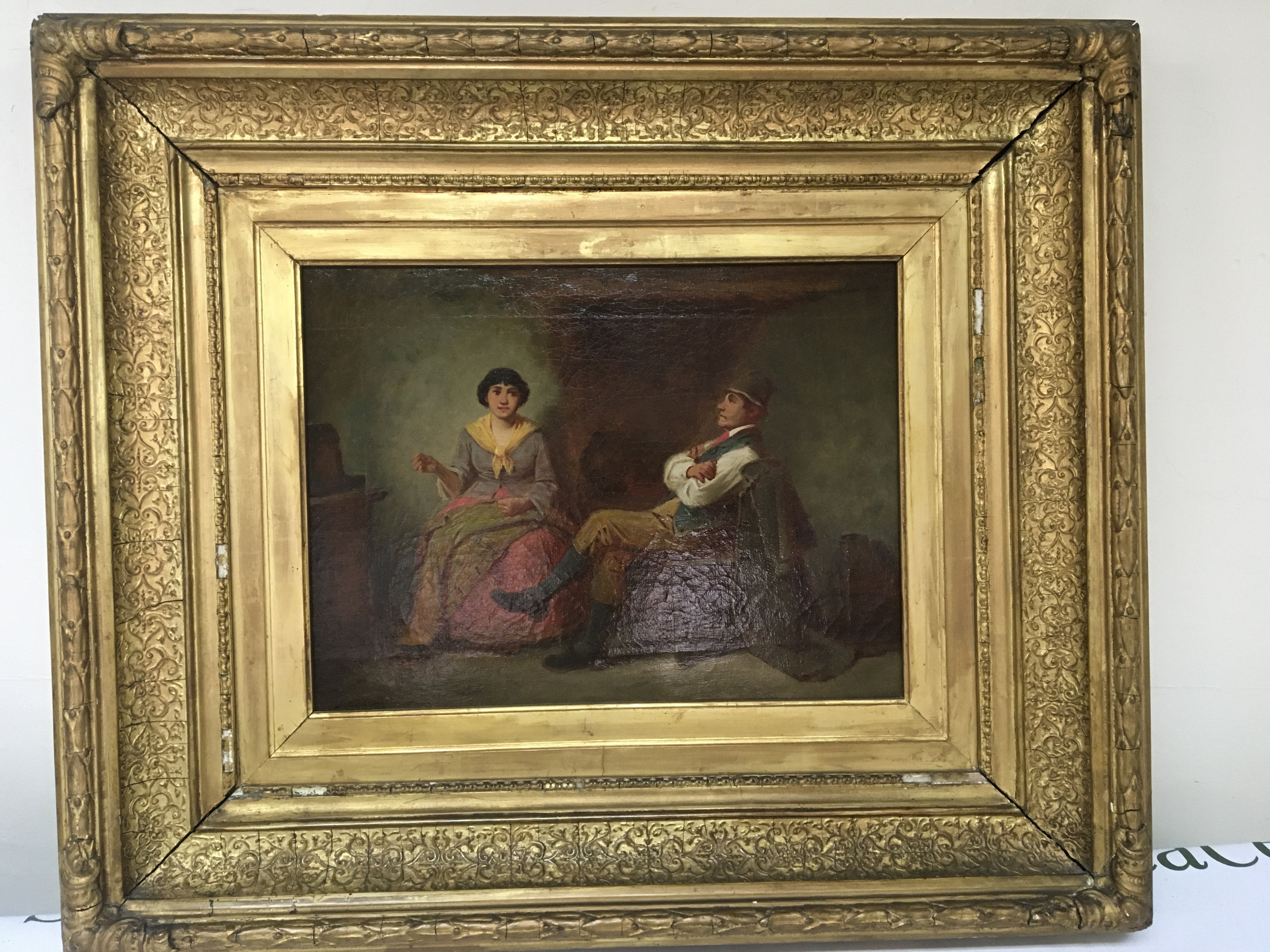 A Continental oil painting on canvas in a wide gilt frame two seated figures in an interior. 71cmx63cm