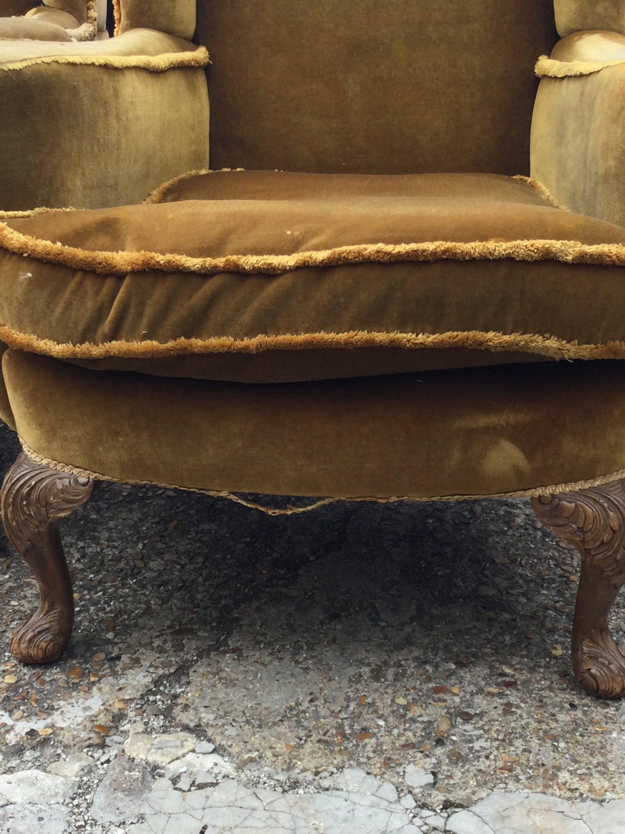 A pair of wing back open armchairs with carved cabriole legs .