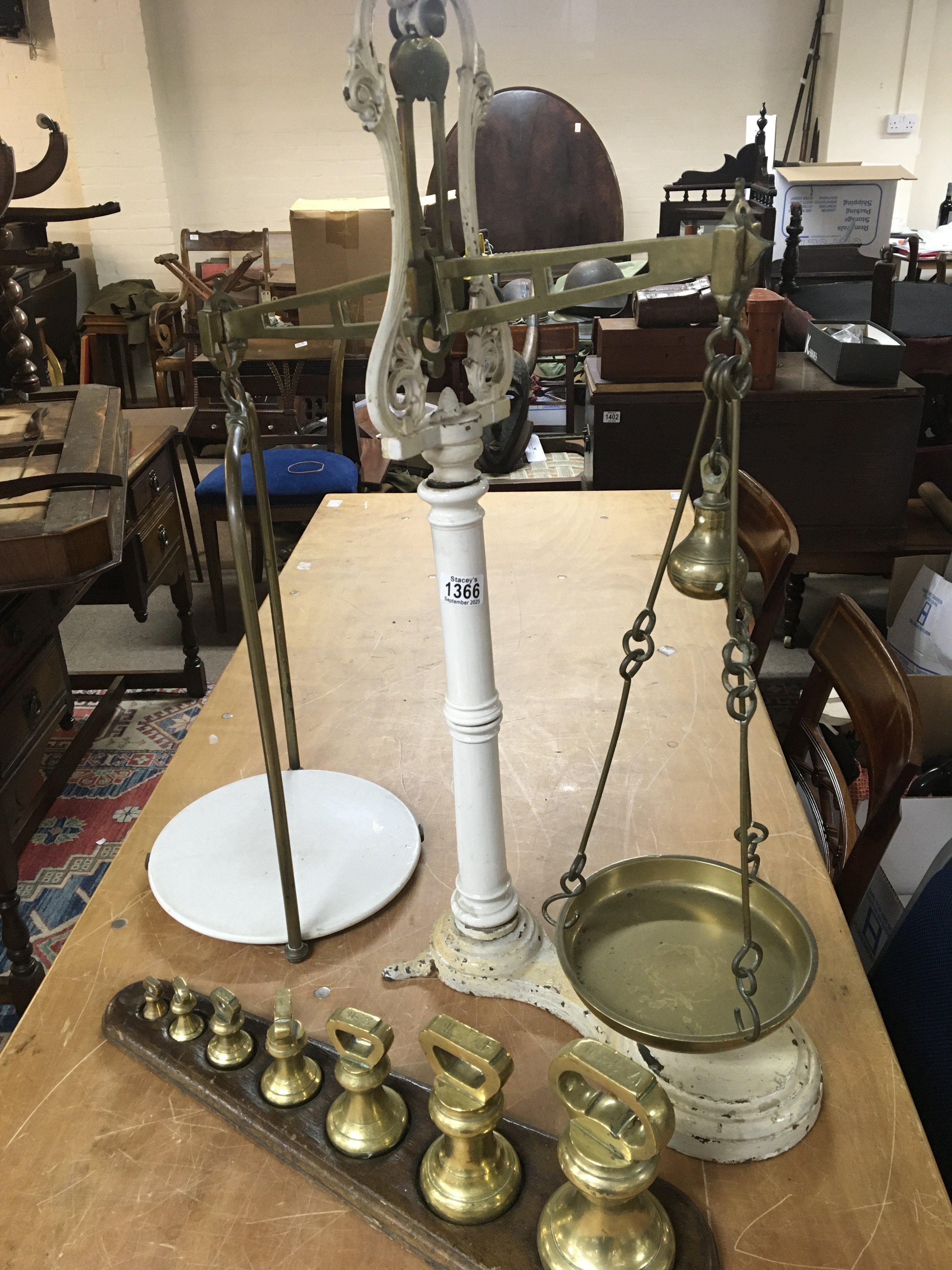 A set of antique enamel beam balance scales with brass fittings and a set of graduating brass bell weights.