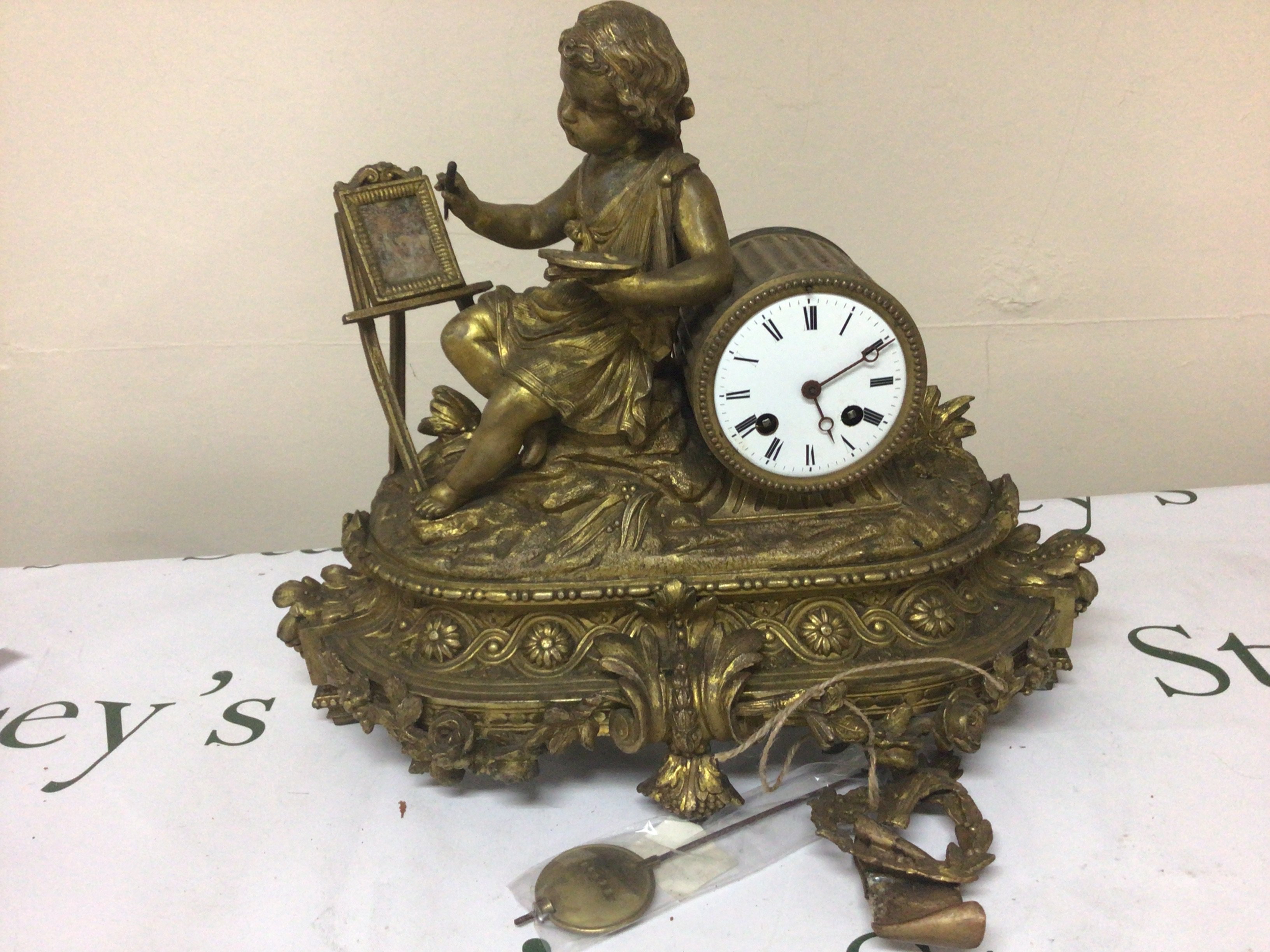 A Fench late 19th century gilt metal clock the case with a young neo classical artist at an easel with pendulum. Makers stamp to the movement Height 35cm width 40cm.