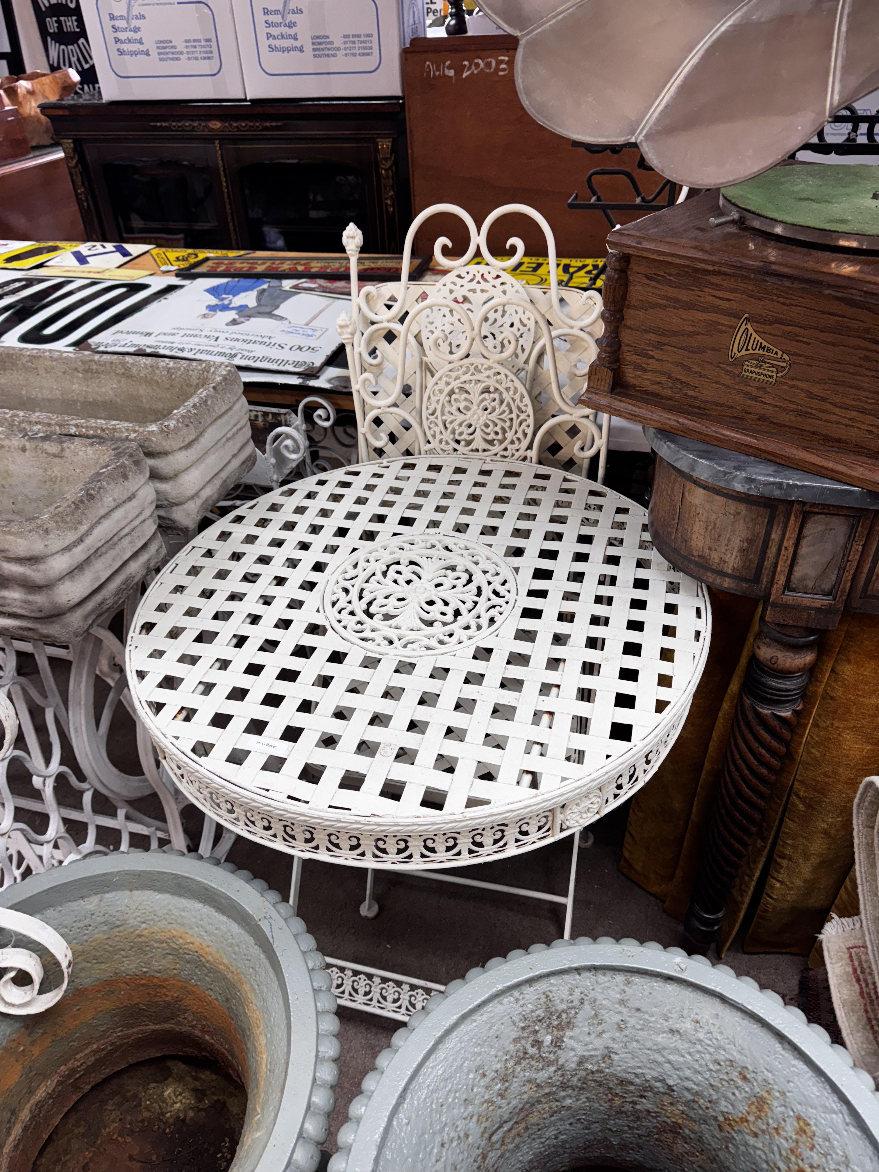 A modern white painted metalwork garden table and 2 chairs.