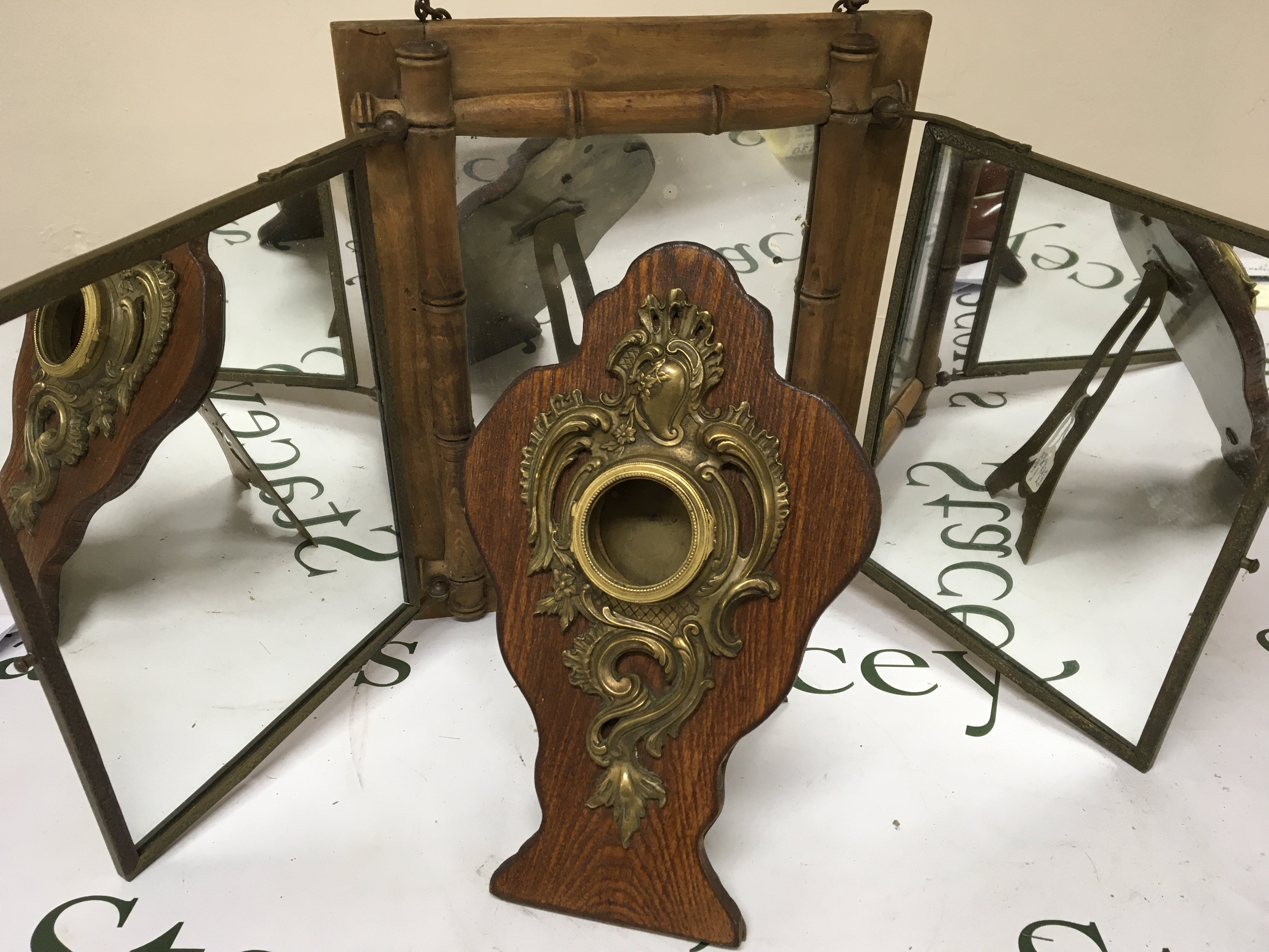 A brass and oak Victorian pocket watch stand Hight 26cm and a simulated bamboo triple mirror frame.