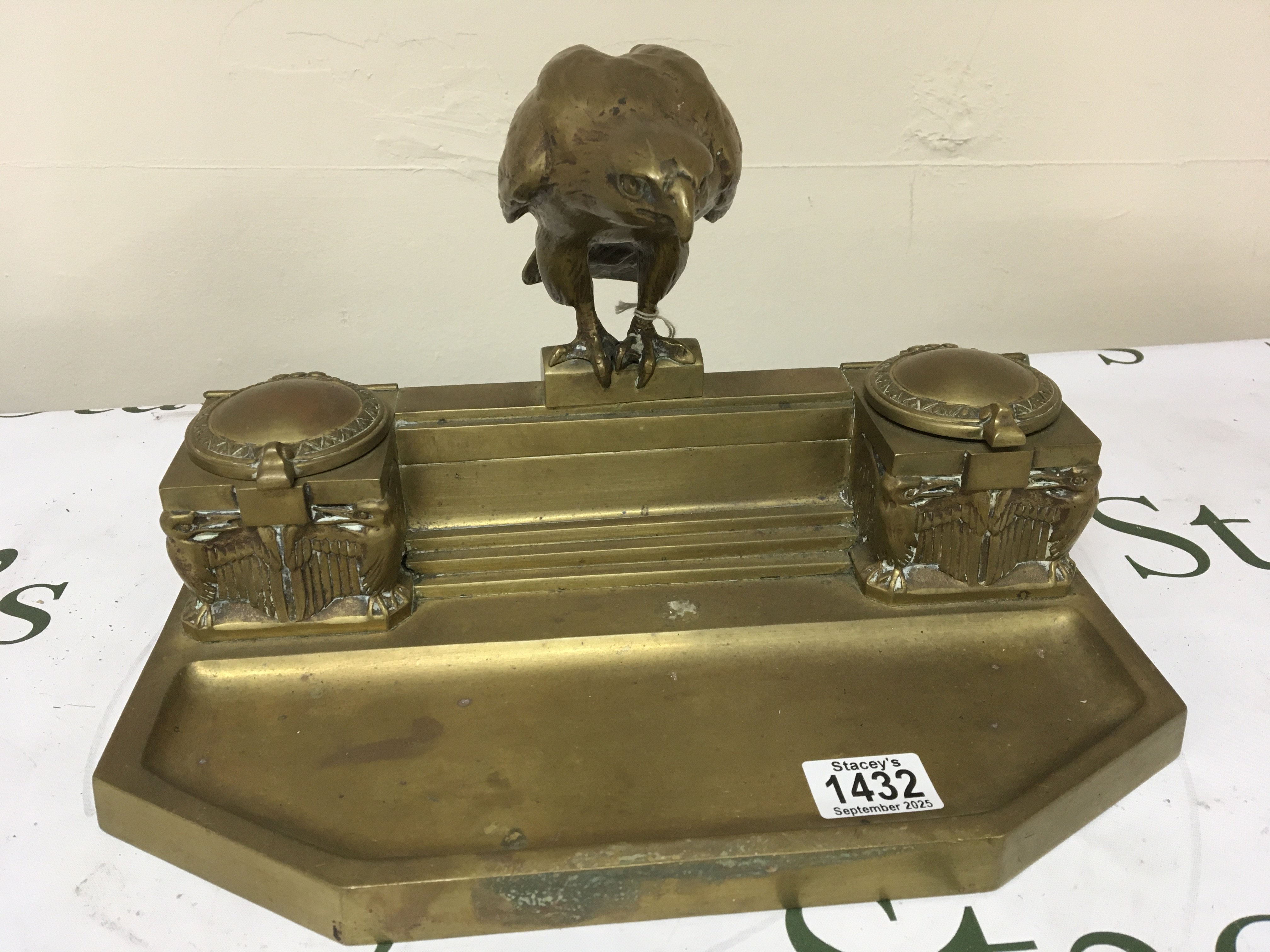 An Art Deco desk top pen tray and inkwell The ink well surmounted with a solid cast Eagle flanked by ink wells. Width 35cm