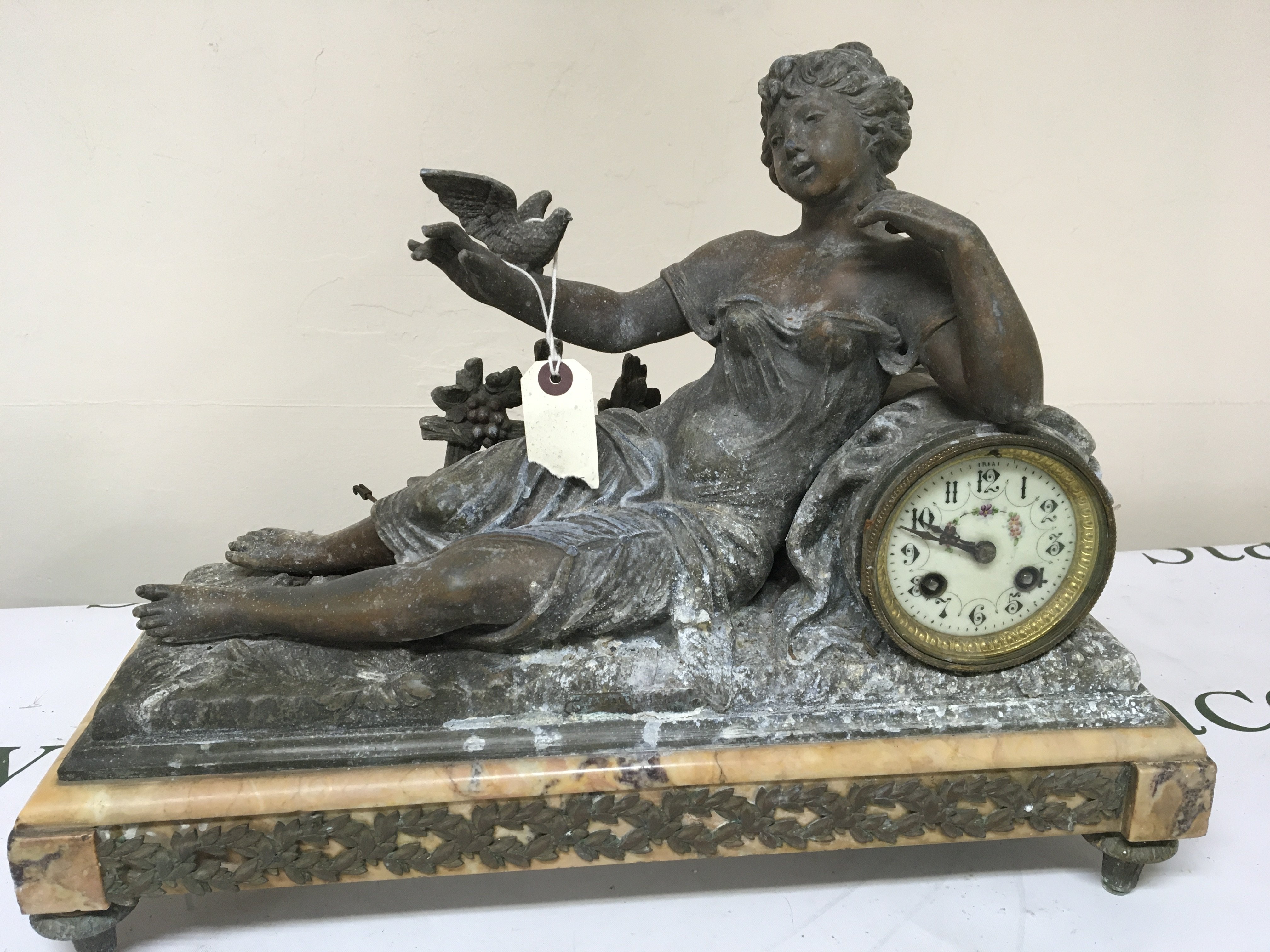 A French late 19th century clock surmounted with a figure of a reclining lady on a marble plinth length 36cm