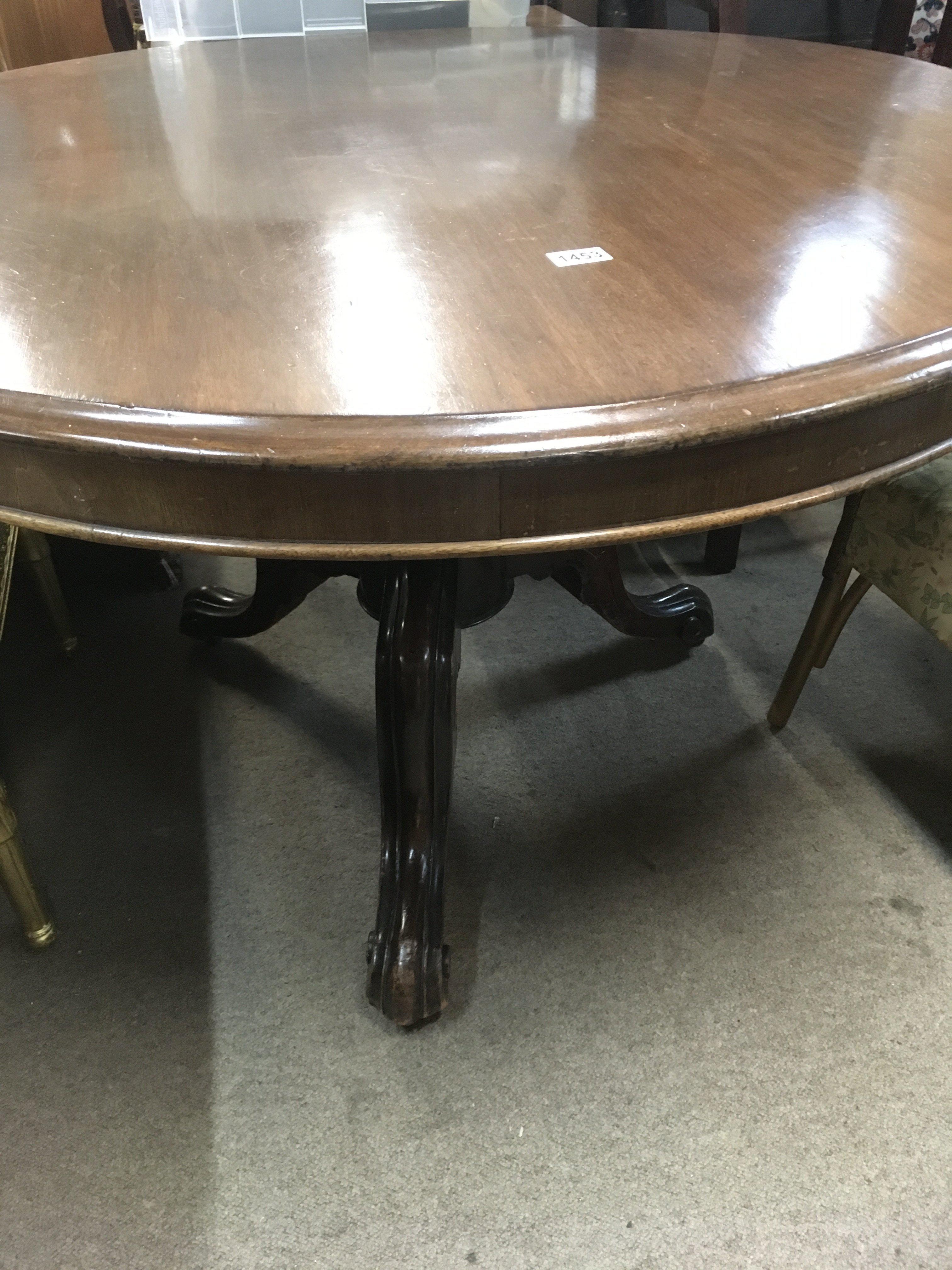 A Victorian mahogany circular dining table on scrolled legs .