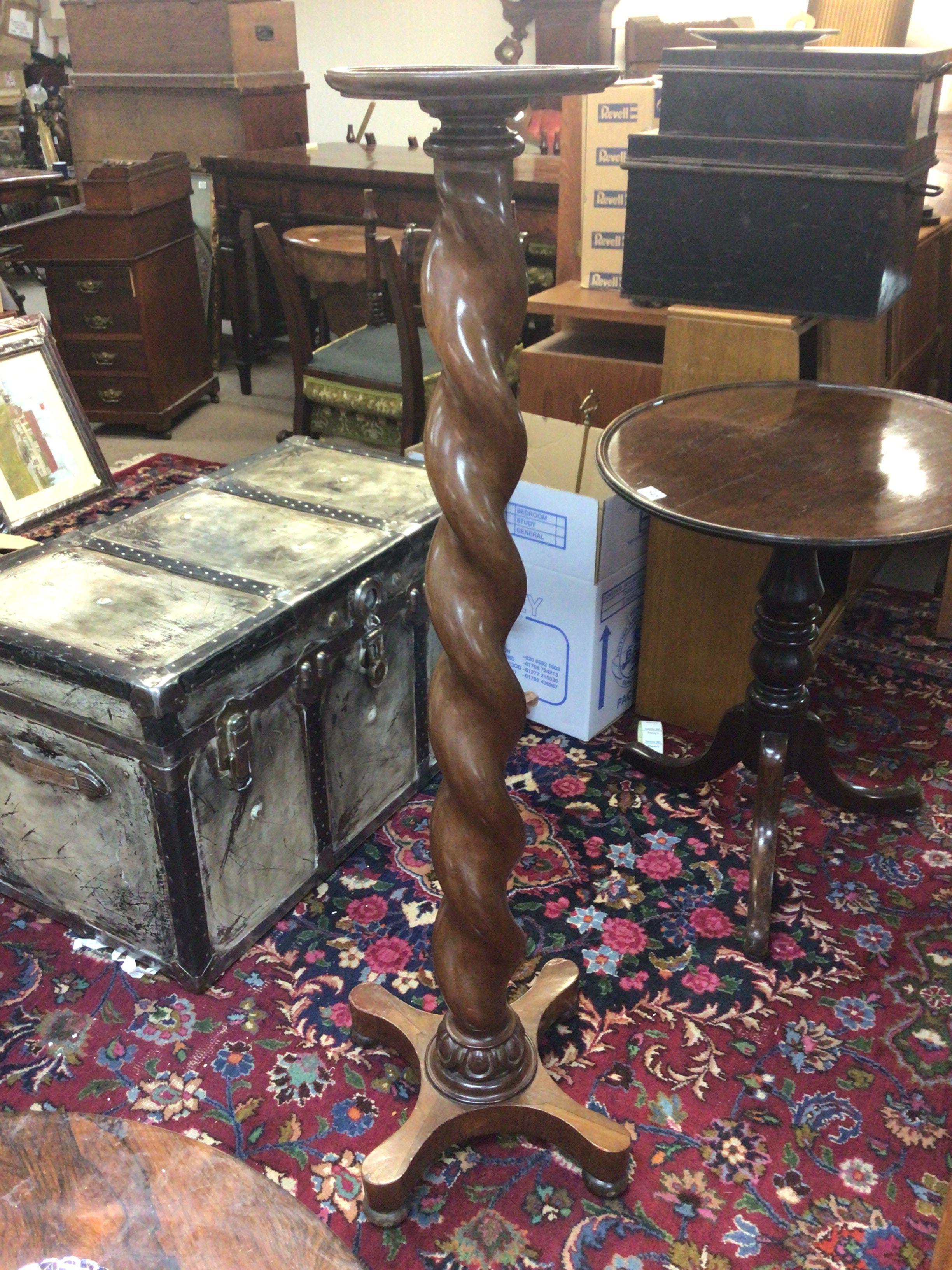 A Walnut plant stand or torcher with a barley twist coloum. Height 126cm