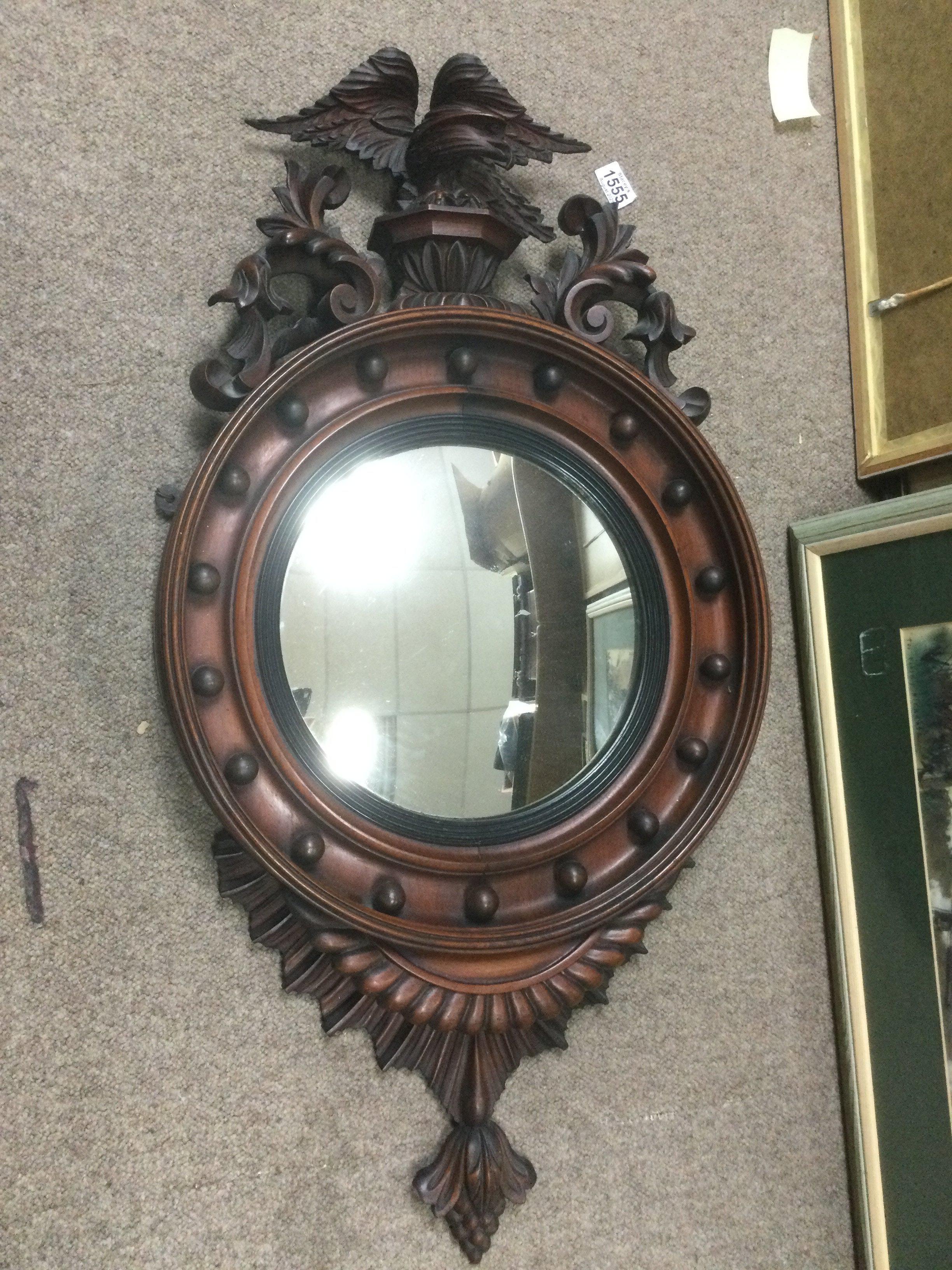 A profusely carved circular convex wall mirror surmounted by an eagle, approx height 93cm. Shipping category D.