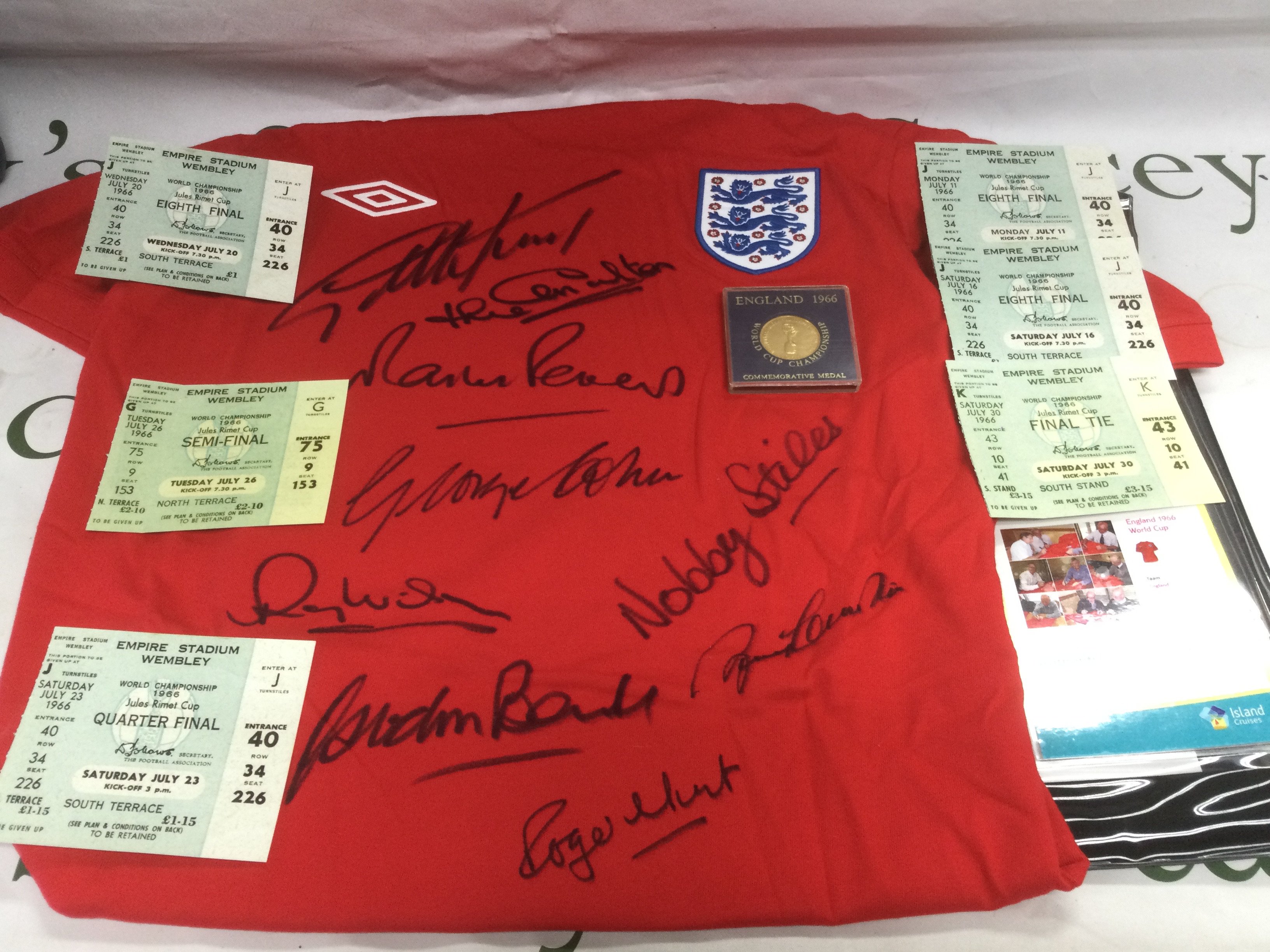 A signed England 1966 World Cup replica shirt plus six tickets from the same championship and a commemorative coin. Shipping category B.