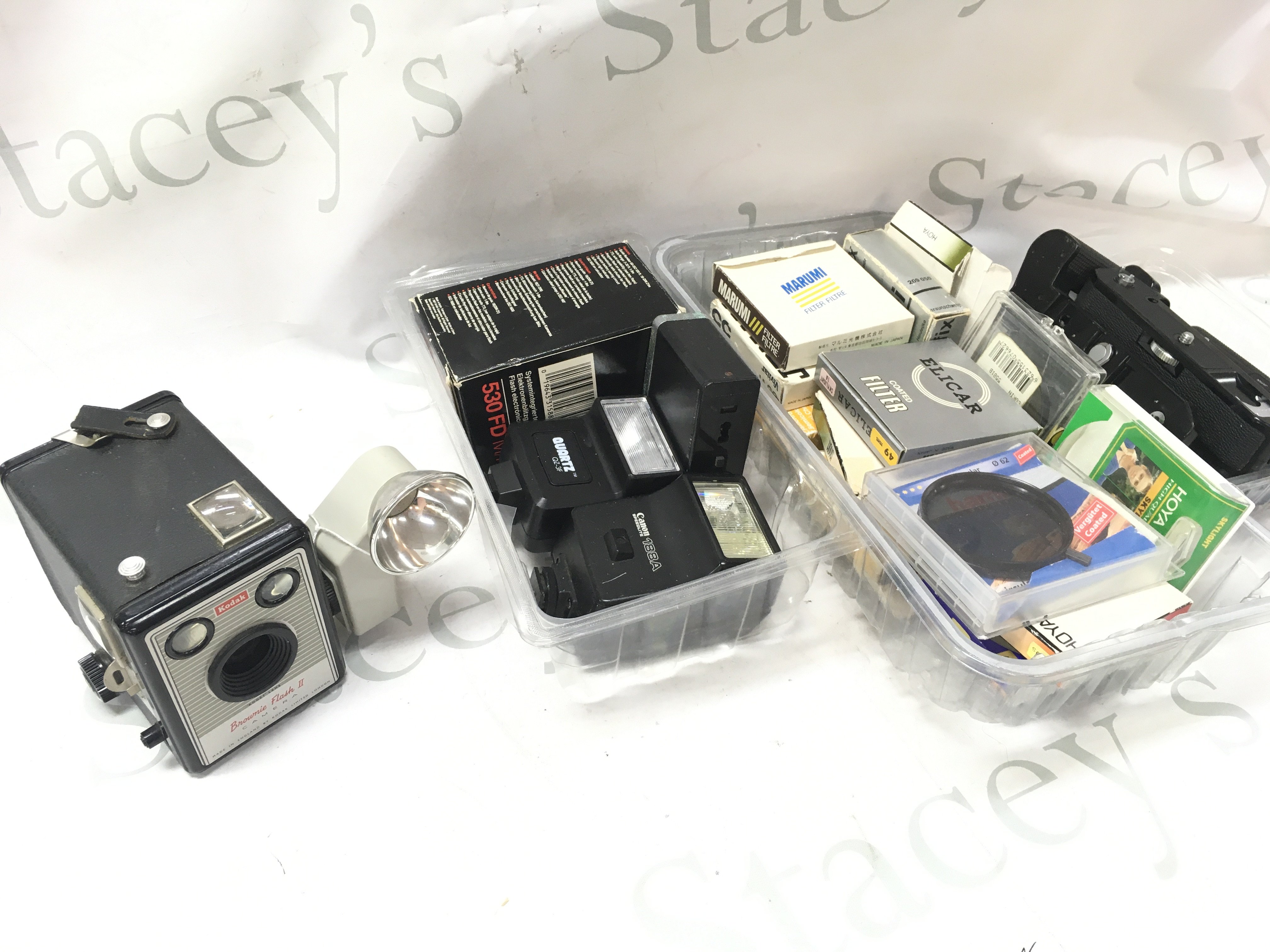 A collection of camera accessories including lenses, filters , grips, flashlights and a Brownie Flash 2 Camera . Postage category C