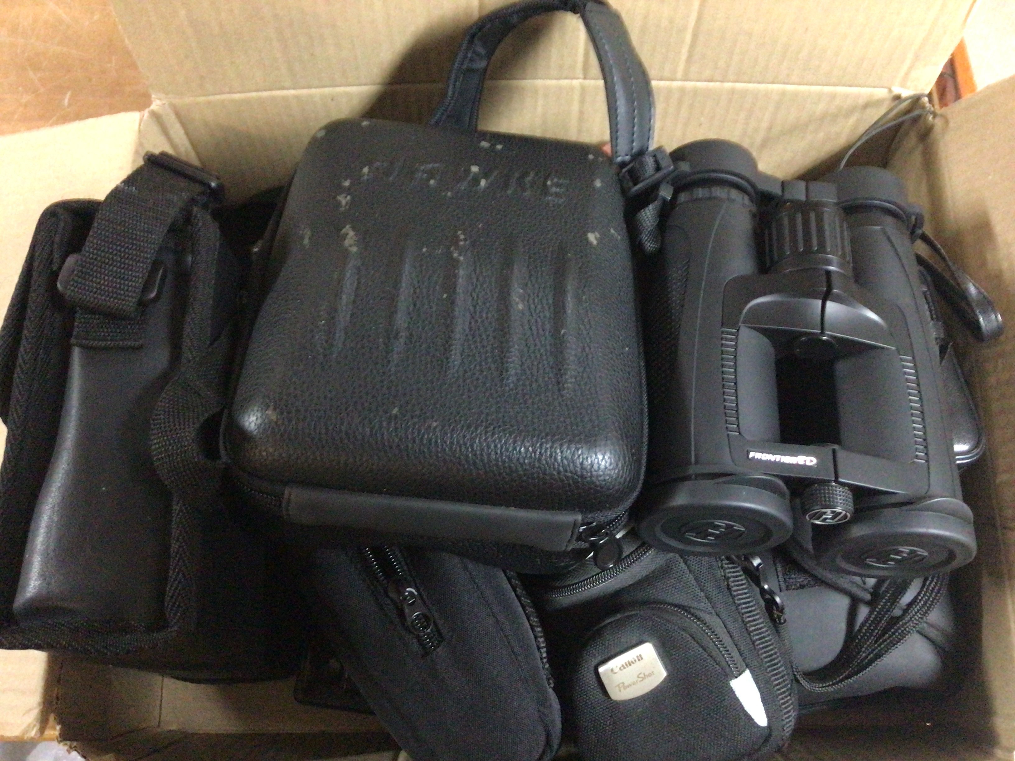 A box containing a collection of cameras and binoculars Canon Frontier binoculars and others.