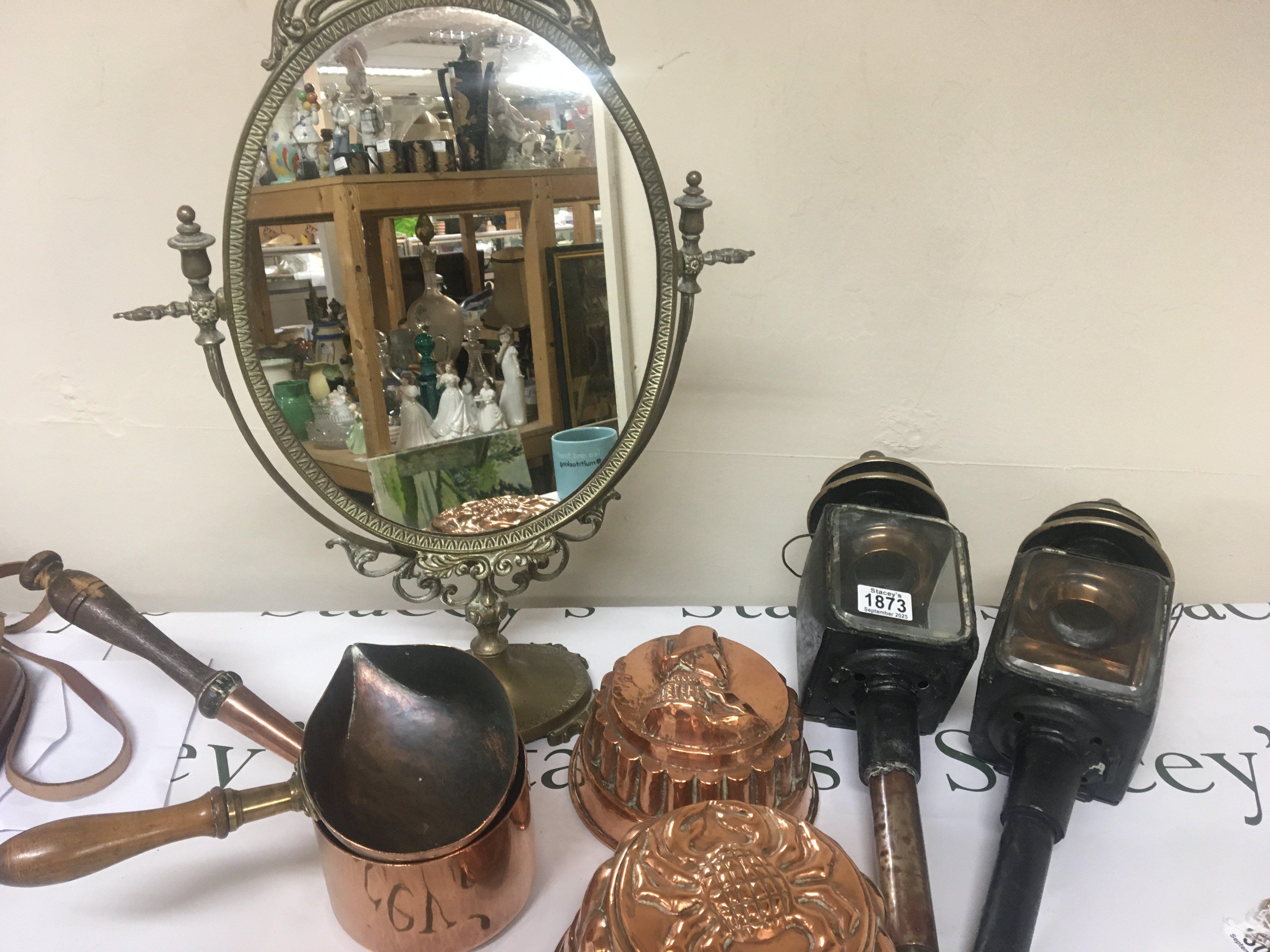 A pair of 19th century coaching lamps a brass mirror copper jelly moulds and copper cooking pots.