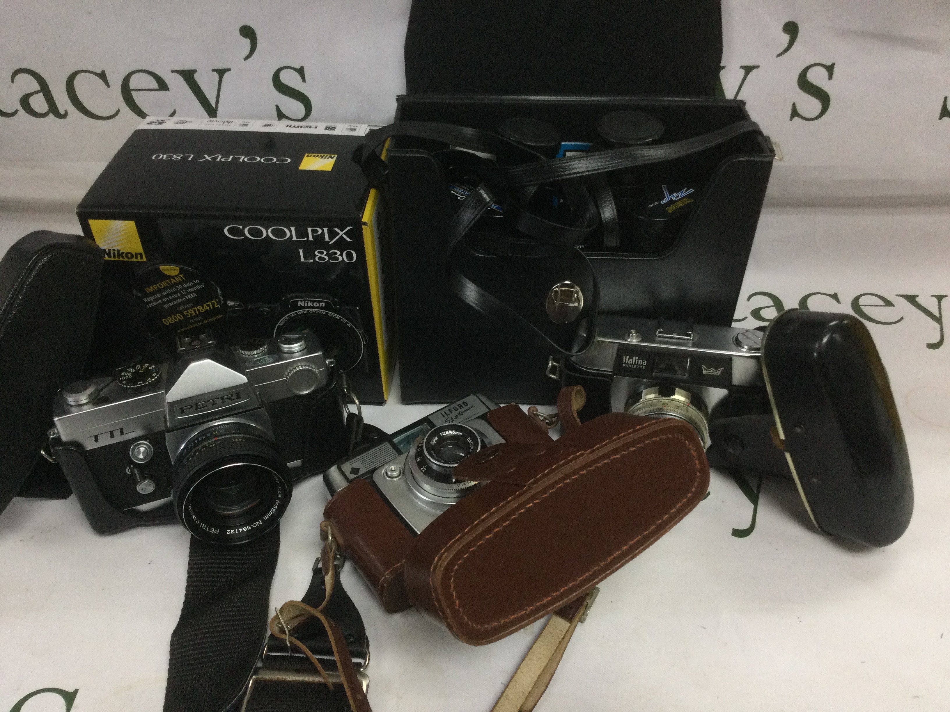 A collection of various cameras and photographic equipment including a Nikon Coolpix L830, Pentax examples and others. Shipping category D.