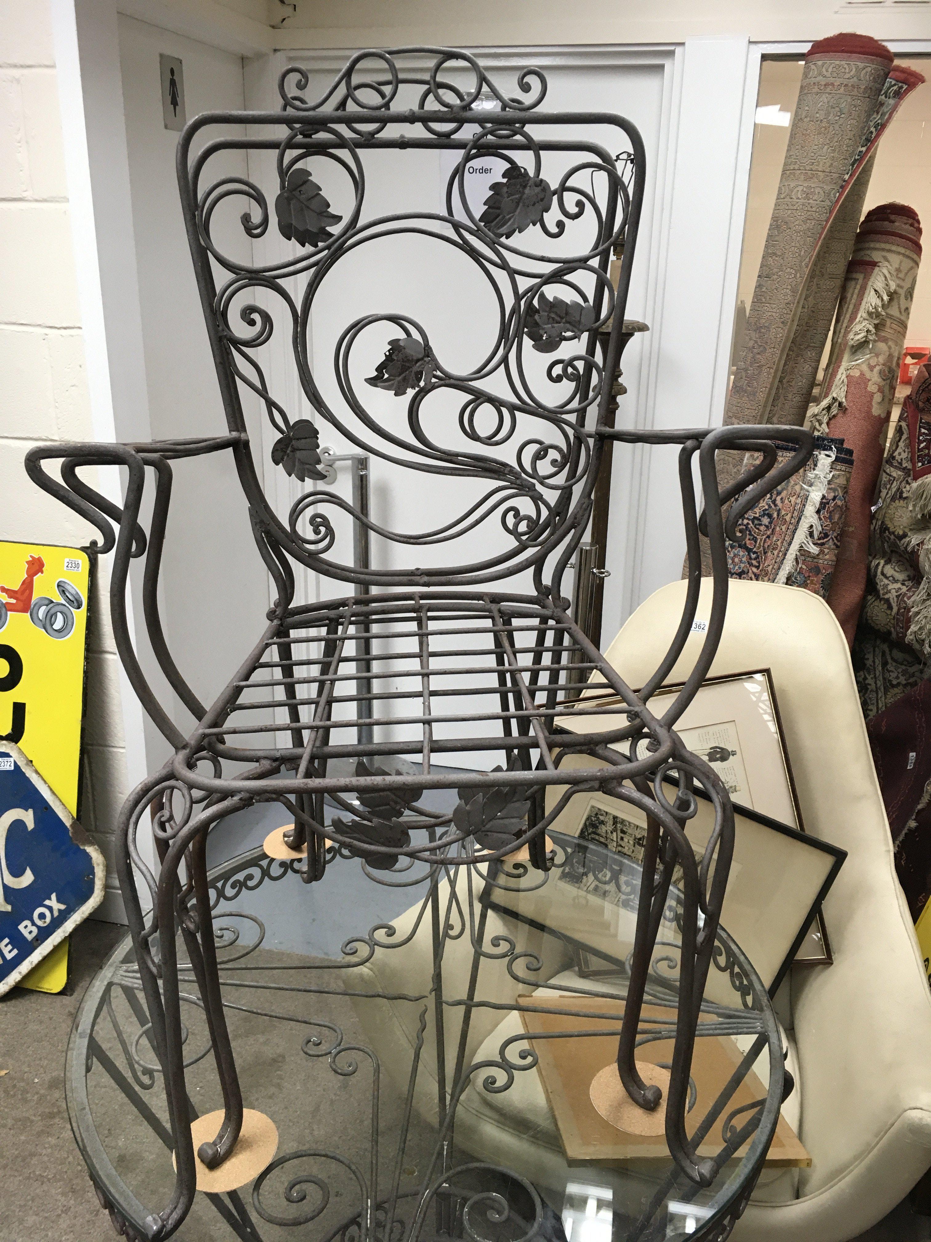 A circular metal garden table with glass top with four chairs