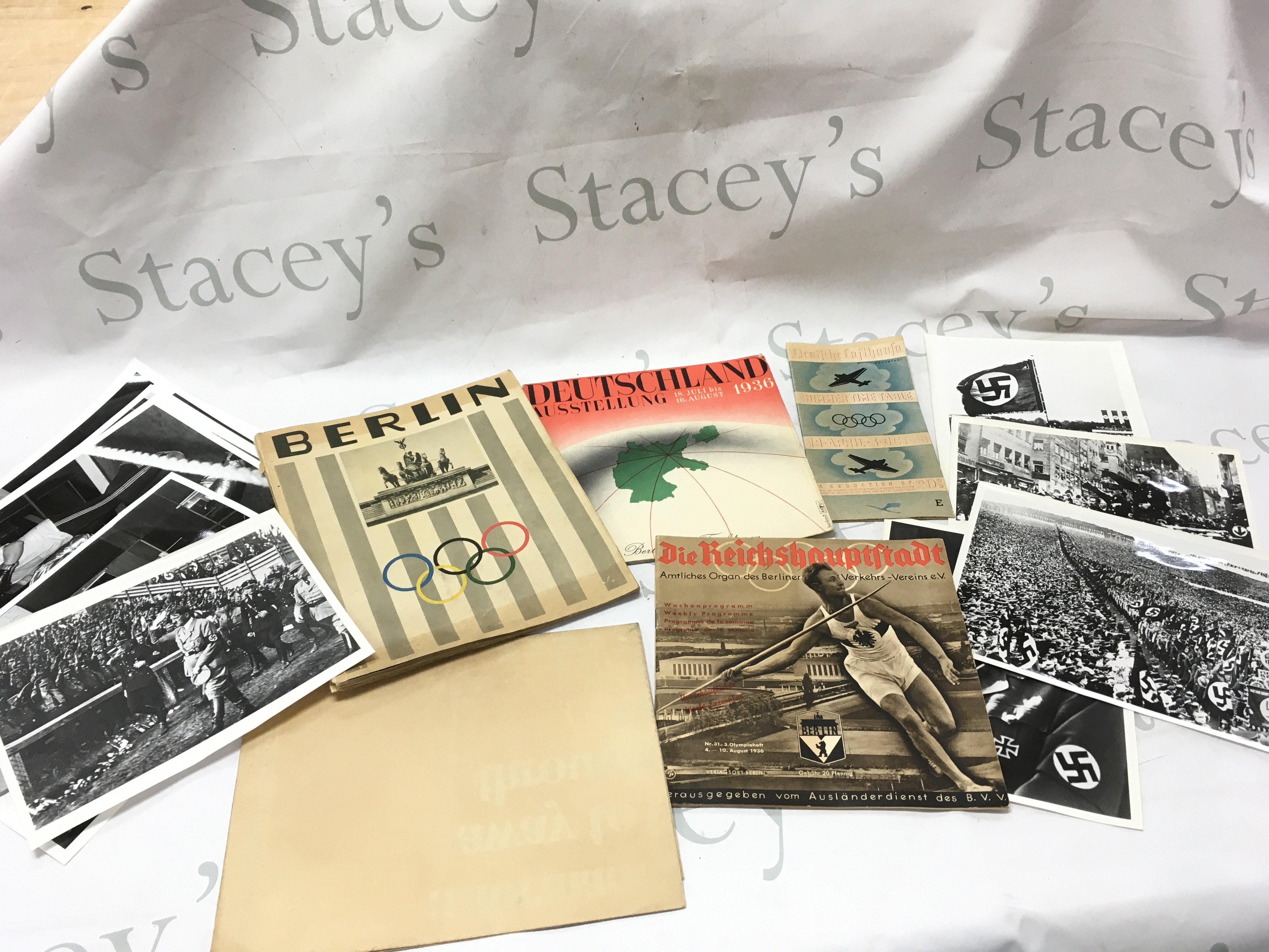 A collection of Nazi Germany ephemera including a Berlin Olympics Photo book Berlin by Hitlers photographer Heinrich Hoffmann with a foreword by Joseph Goebbels. Printed: Berlin, Verlag Heinrich Hoffmann in 1936, Herbert Bayer Deutschland Ausstellung 1936, Deutsche Lufthansa April 1936 airline time table schedule brochure, The Reich Capital 31/1936 &#2013265924&#2013265923&#2013265921 Official Organ of the Berlin (Berliinin olympialaiset) booklet. British HM stationary be on your guard poster , imperial war museum prints. Postage category B