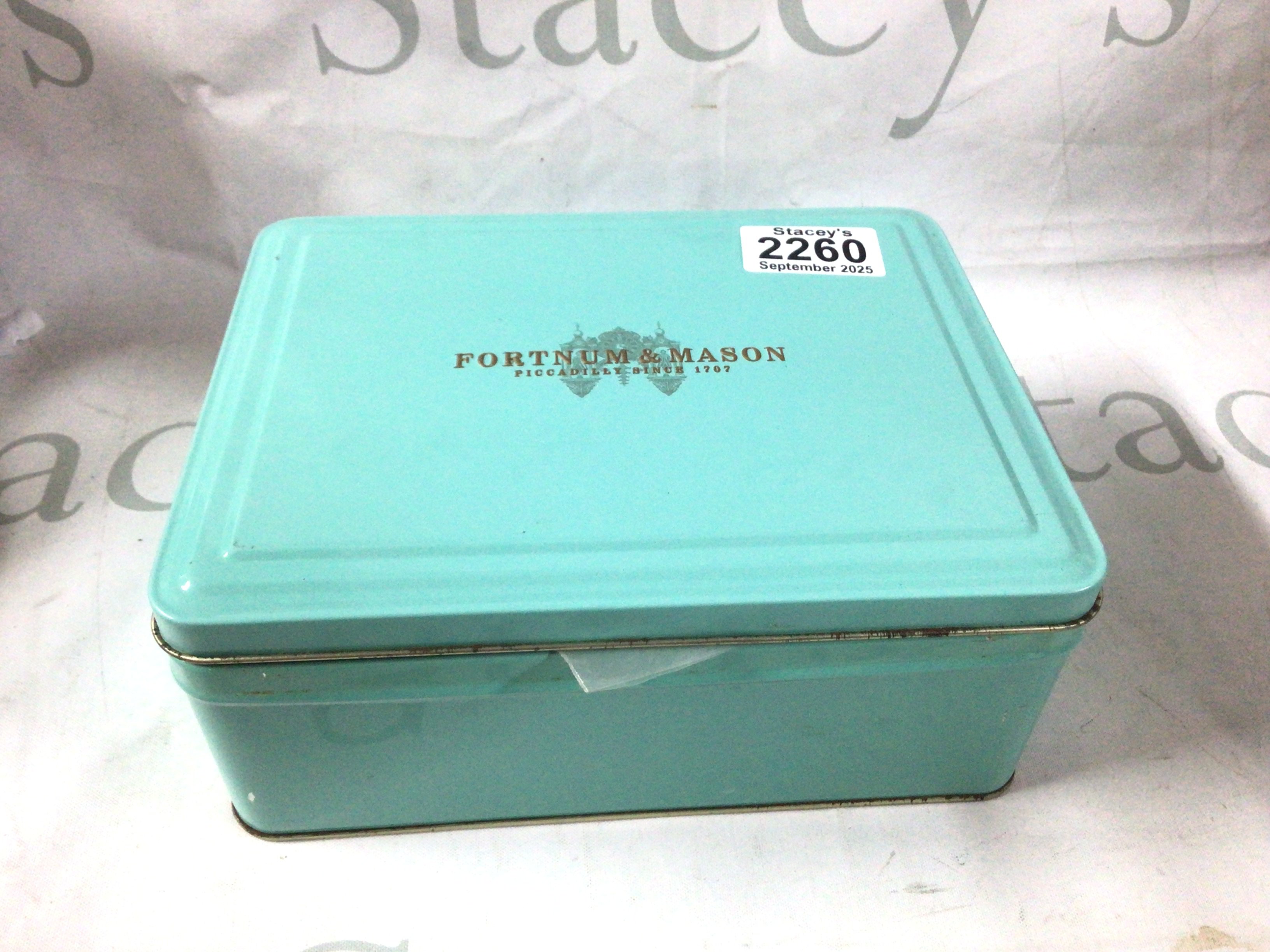 A vintage fortnum and mason tin filled with antique lighters and some accessories.